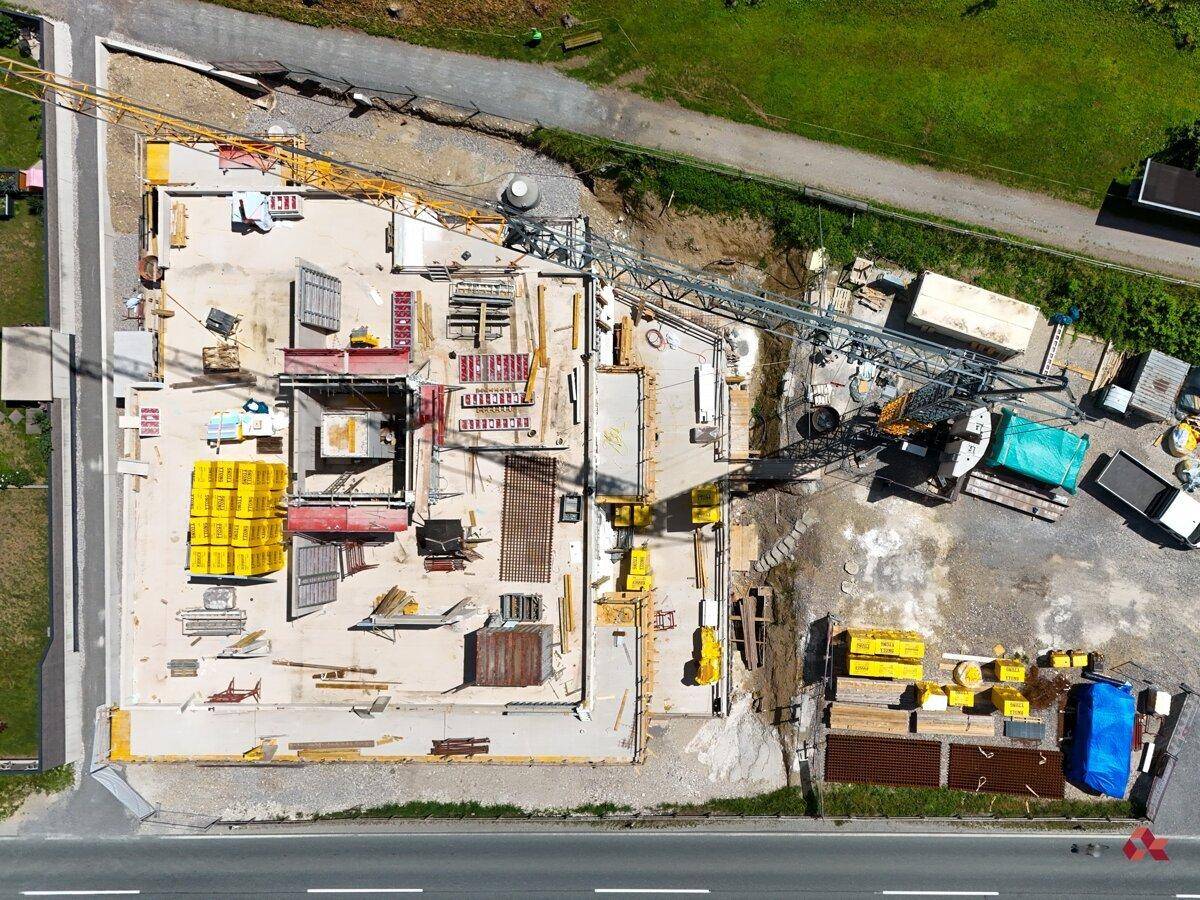 Vogelperspektive der Baustelle mit Grundriss des Gebäudes und Baumaterialien, angrenzend an eine Straße.