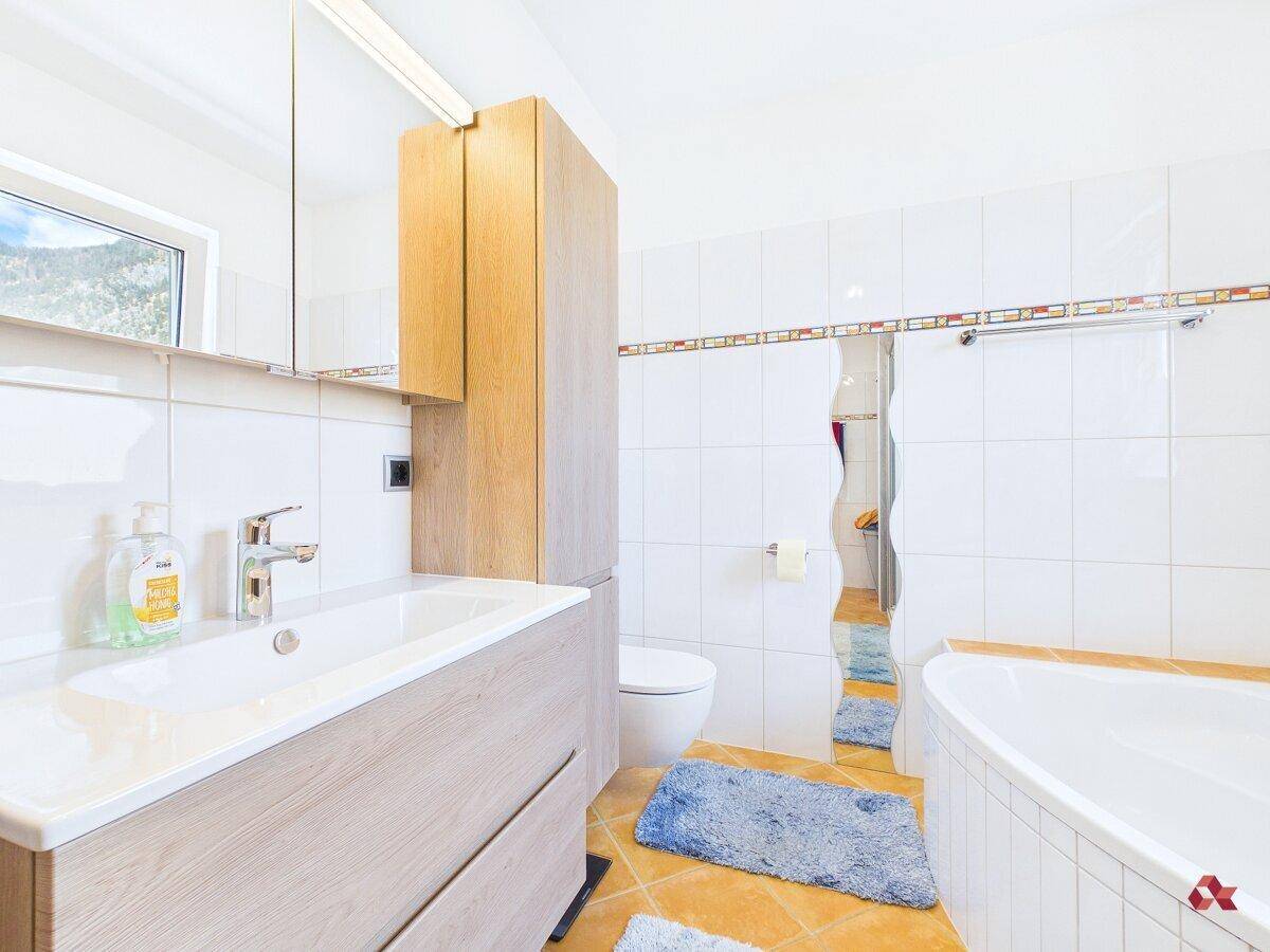 Badezimmer mit Badewanne, Waschbecken, WC und hellen Fliesen.