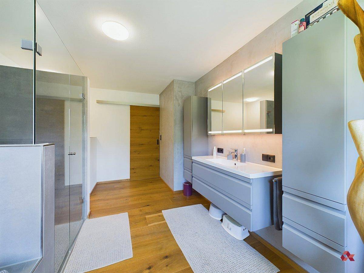 Modernes Badezimmer mit Doppelwaschbecken, beleuchtetem Spiegelschrank und praktischer Schiebetür.
