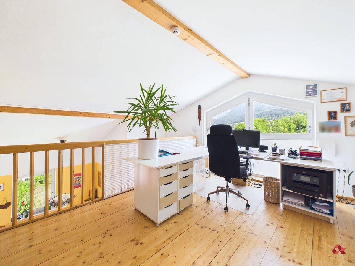 Geräumiges Büro im Dachgeschoss mit Holzfußboden und offener Galerie zum darunterliegenden Bereich.