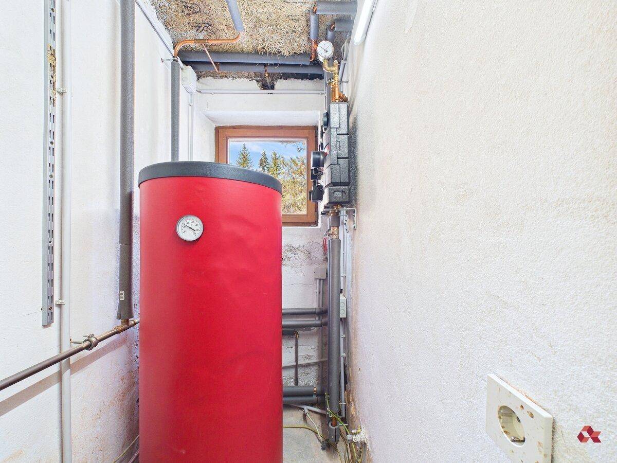 Heizungsraum mit Warmwasserspeicher und technischen Installationen.