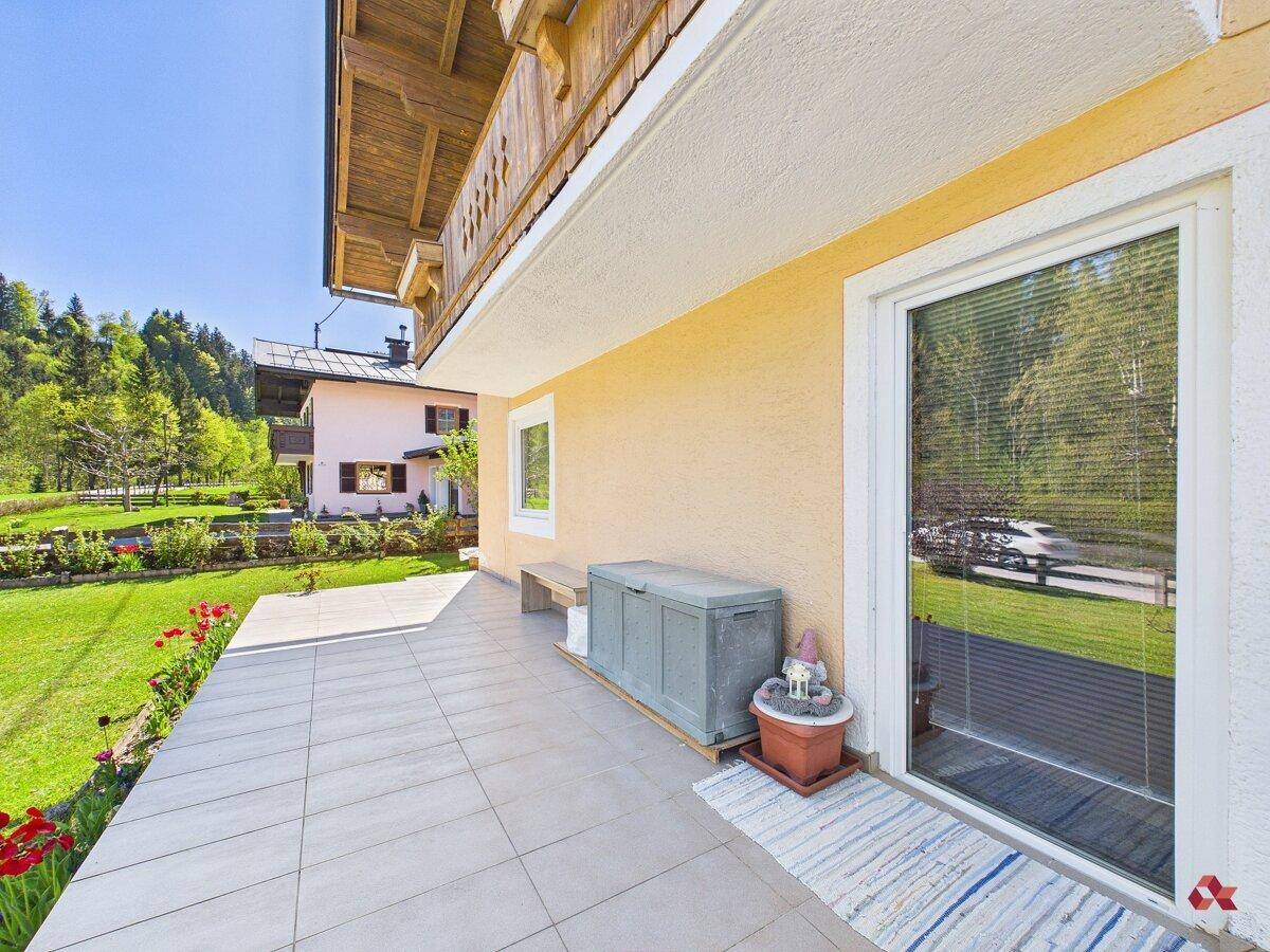 Gemütliche Terrasse mit Fliesenboden und Zugang zum Garten, ideal zum Entspannen.