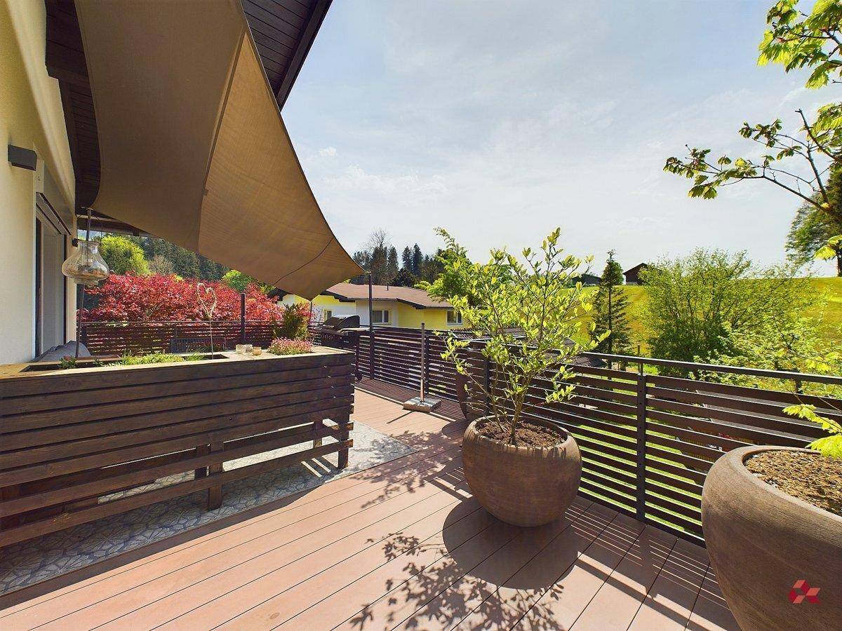 Geräumige Terrasse mit Holzdeck, Pflanzenkübeln und weitem Blick auf die umliegende Landschaft.