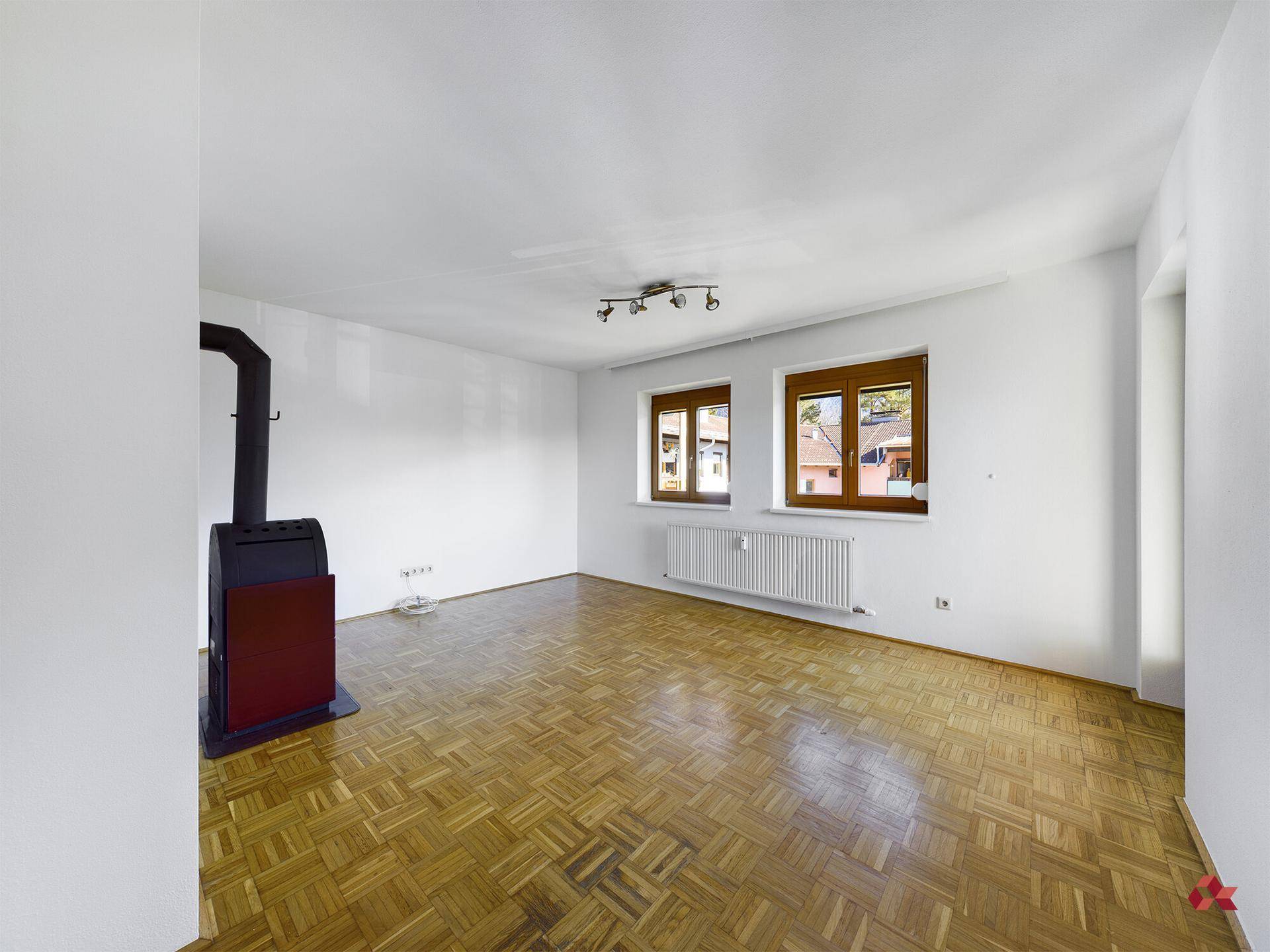 Geräumiger Raum mit Parkettboden und einem modernen Holzofen als Heizquelle.