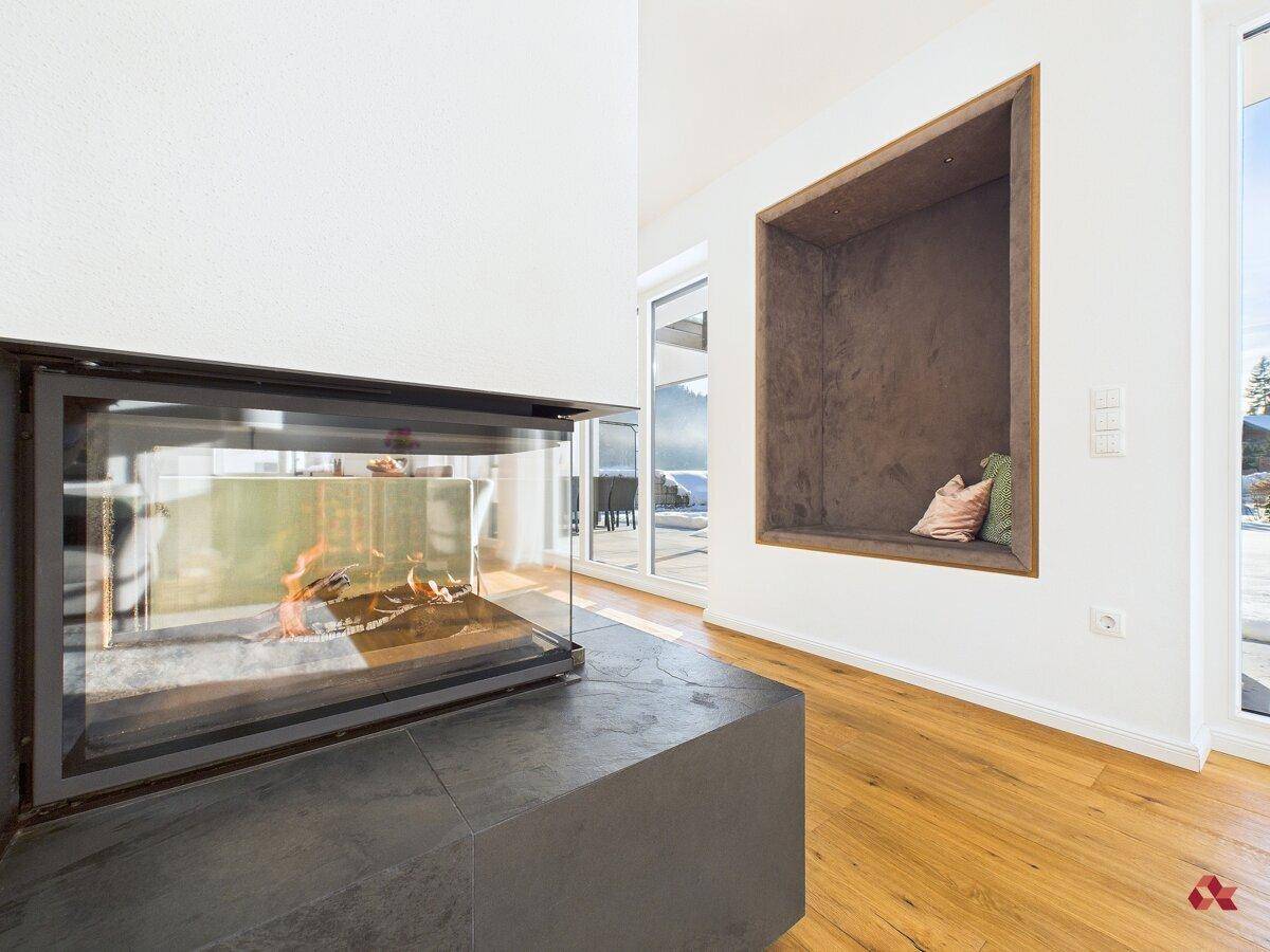 Moderner Kamin im Wohnbereich mit gemütlicher Sitzecke und Holzboden.