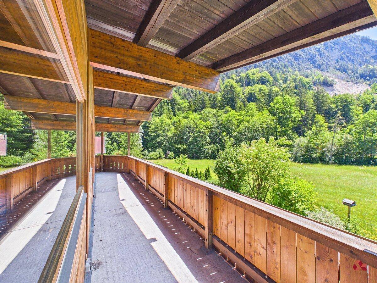Sonniger Holzbalkon mit freiem Blick auf die dichten Wälder und die imposanten Berge.