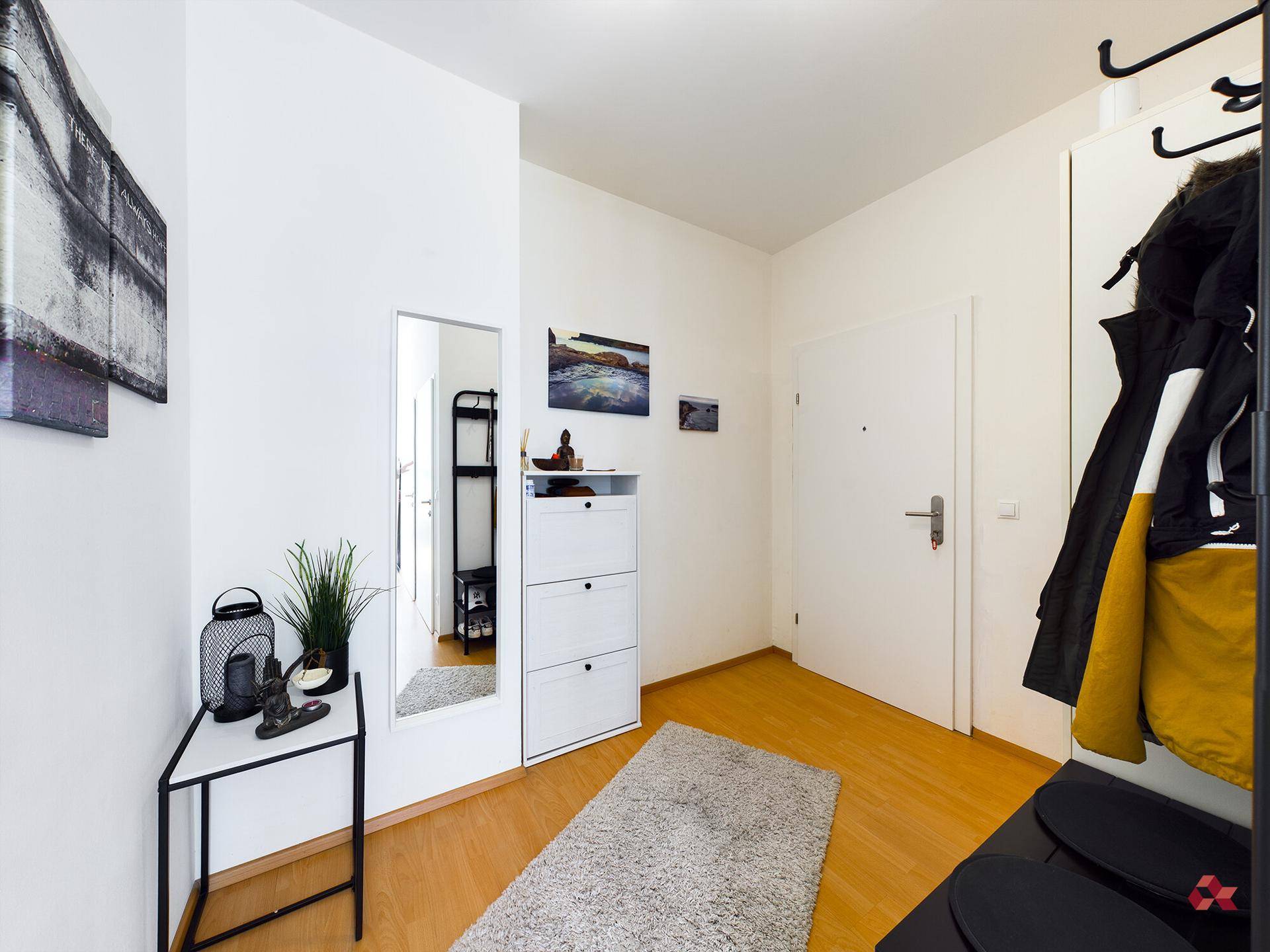 Heller Eingangsbereich mit Garderobe, Spiegel und praktischem Schuhschrank.
