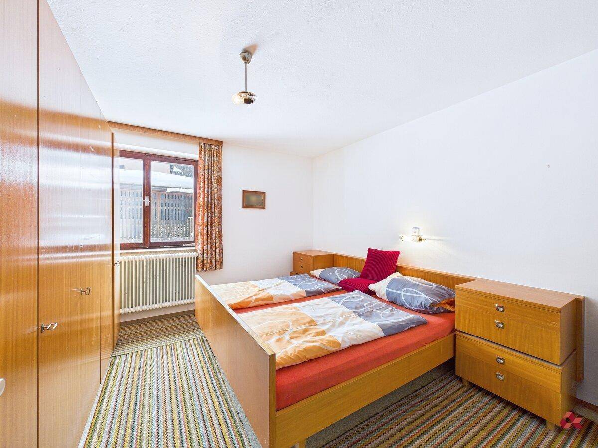 Helles Schlafzimmer mit Doppelbett, Kleiderschrank und Teppichboden.