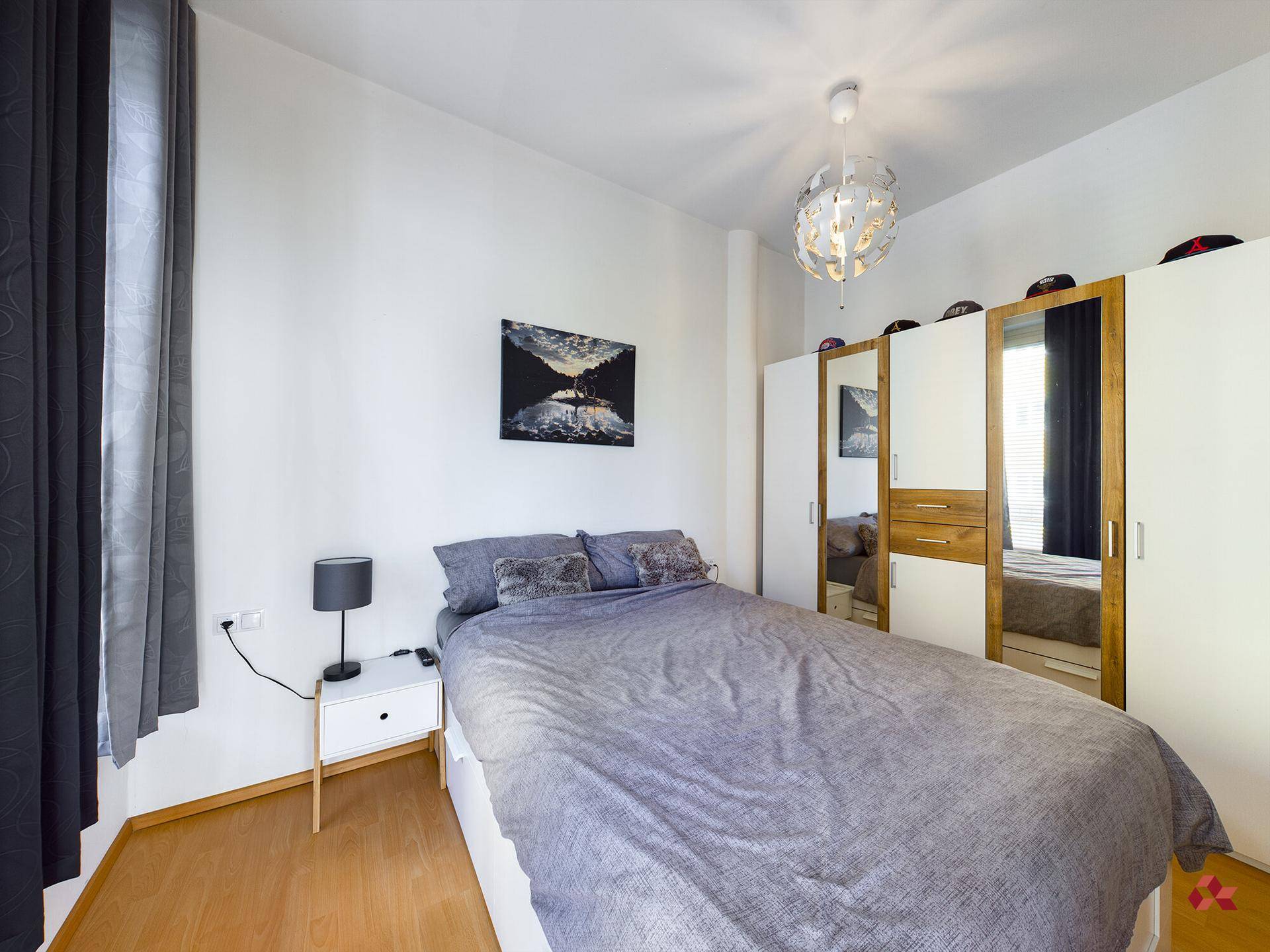 Schlafzimmer mit Doppelbett, Nachttisch und großem Kleiderschrank mit Spiegeltüren.