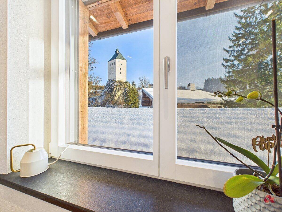 Fensterblick auf einen historischen Turm und die verschneite Winterlandschaft.