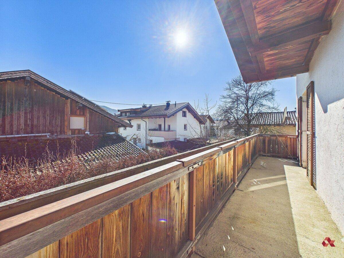 Langer Holzbalkon mit Blick auf die umliegenden Häuser und sonnige Umgebung.