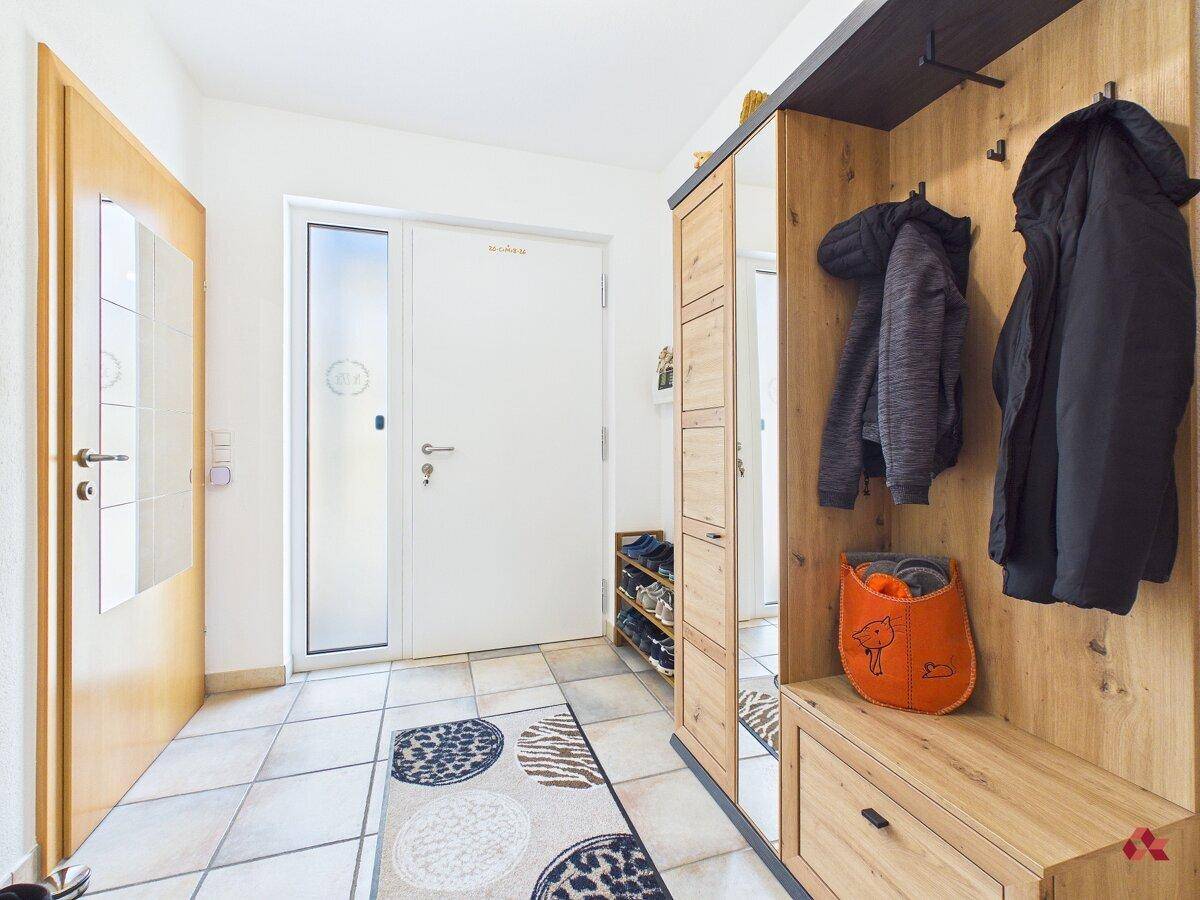 Heller Eingangsbereich mit Garderobe, Schuhregal und Fliesenboden.