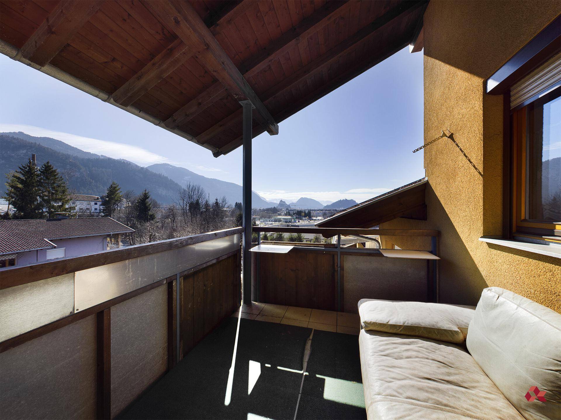 Sonniger Balkon mit Sitzbank und weitem Blick auf die umliegende Berglandschaft.