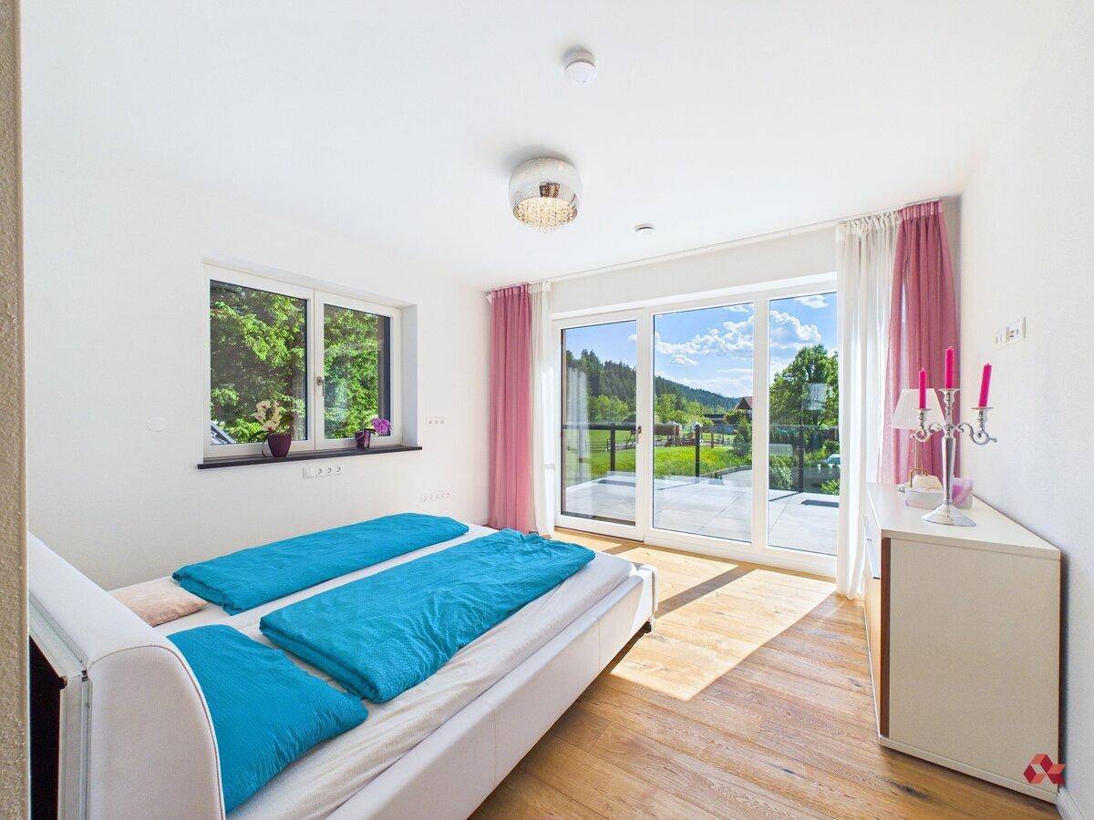 Freundliches Schlafzimmer mit Doppelbett, Holzboden und weitem Blick ins Grüne.