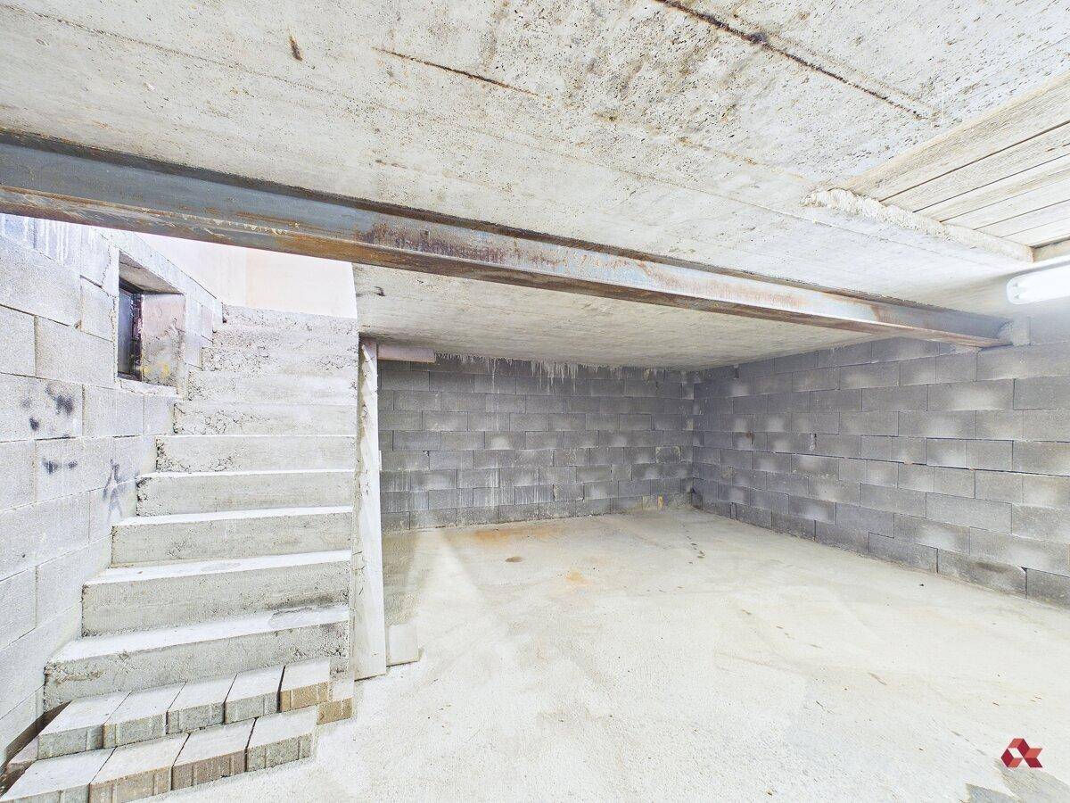 Unfertiger Kellerraum mit Betonwänden und Treppenaufgang, bietet viel Stauraum.