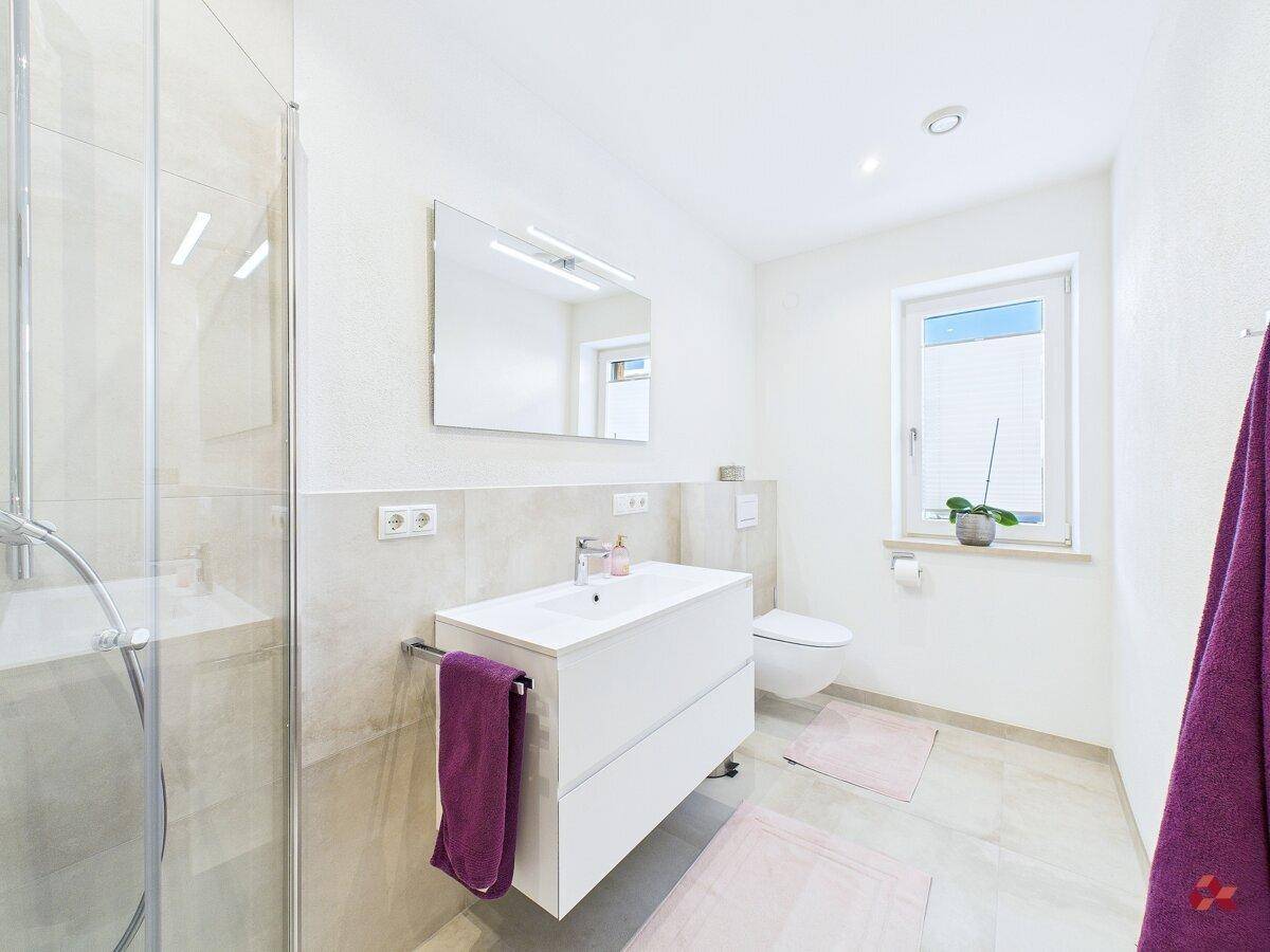 Helles Badezimmer mit Dusche, Einzelwaschbecken und WC.