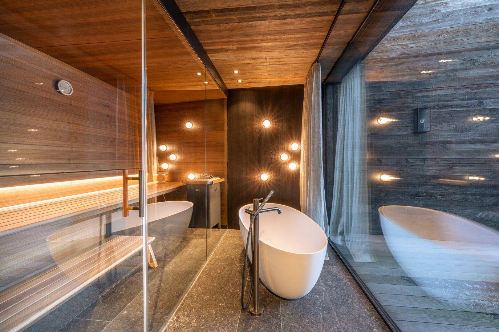 Luxuriöses Badezimmer mit freistehender Badewanne, integrierter Sauna und Panoramablick.