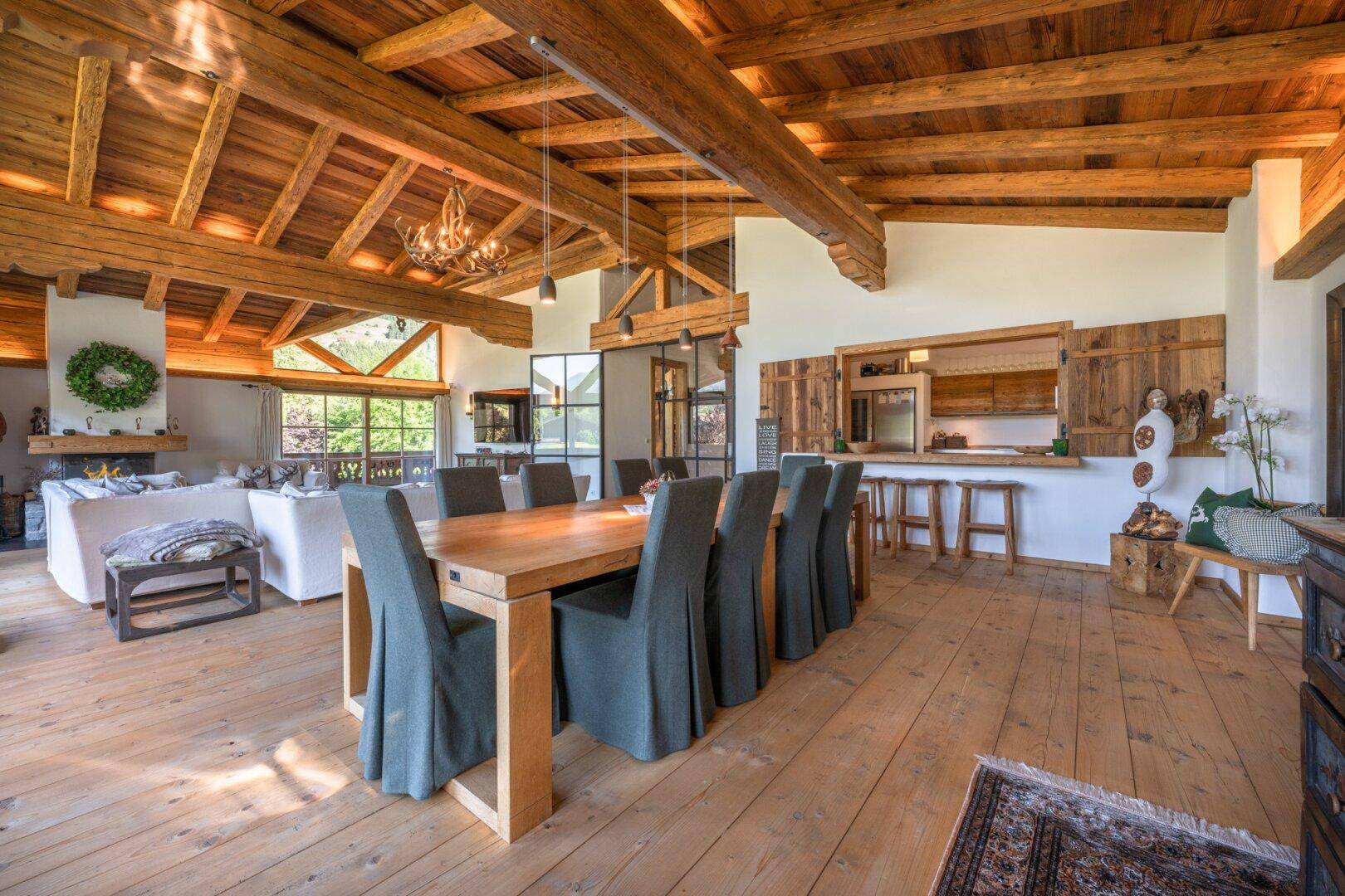 Offener Essbereich mit Holztisch und Zugang zu einer rustikalen Küche mit Holzfronten.