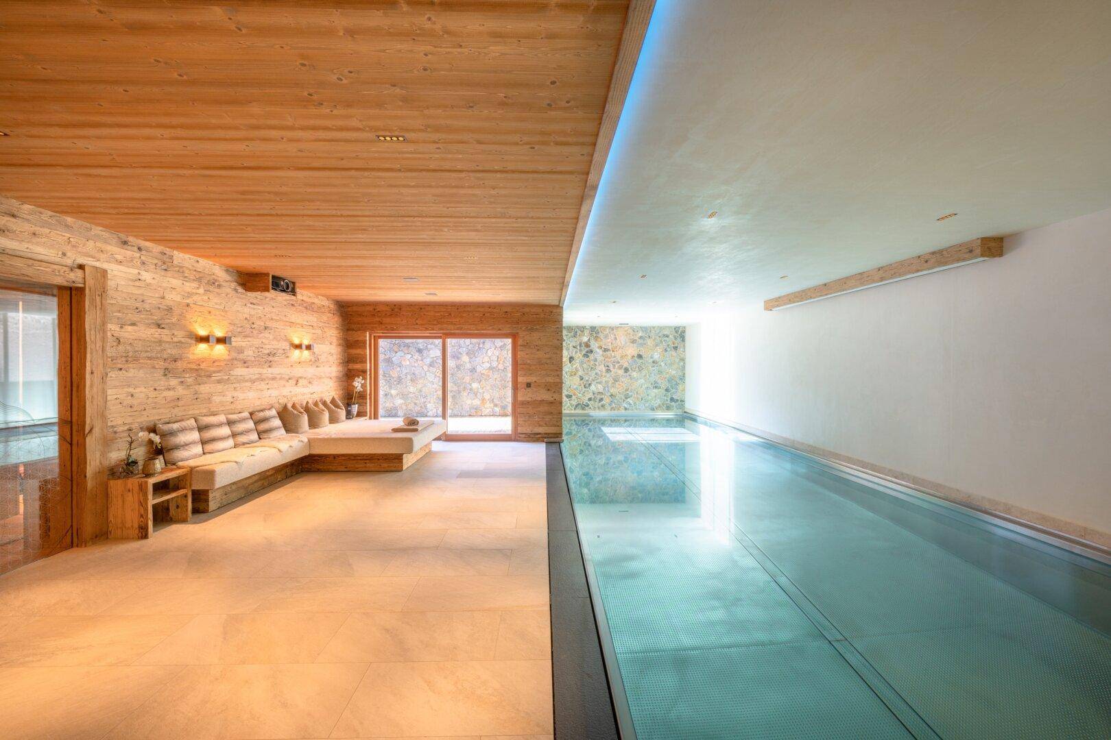 Großzügiger Innenpoolbereich mit Liegeflächen und Holzwänden für Entspannung.