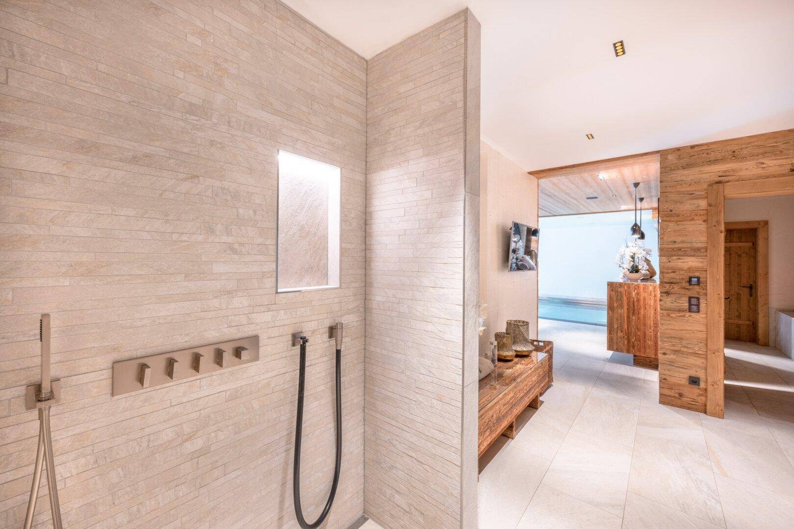 Elegante Duschkabine mit Steinwandfliesen und modernen Armaturen im Wellnessbereich.