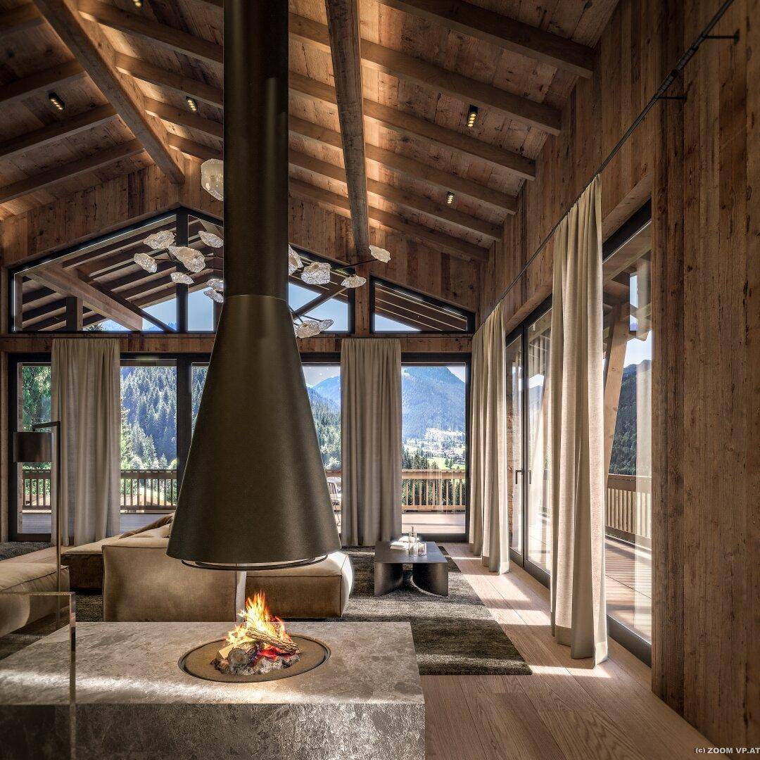 Gemütliches Wohnzimmer mit modernem Kamin, Holzwänden und weitem Blick auf die Berge.