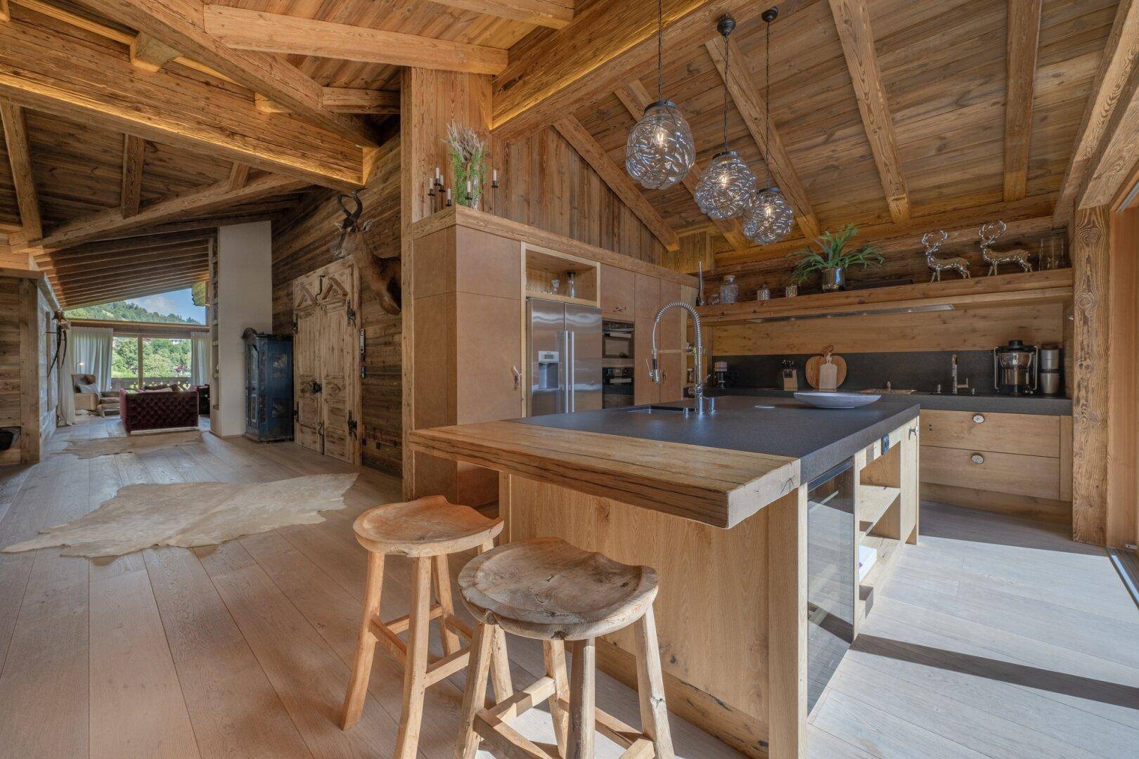 Moderne Holzküche mit Kochinsel, integrierten Geräten und offenem Blick in den Wohnbereich.