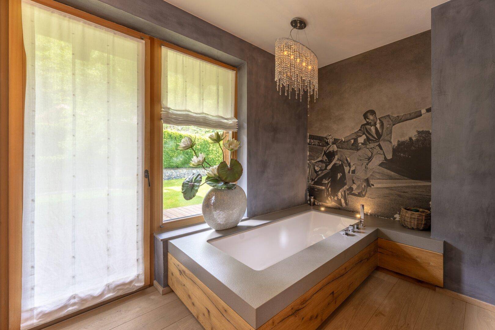 Modernes Badezimmer mit eingebauter Badewanne, Holzakzenten und Blick ins Grüne.
