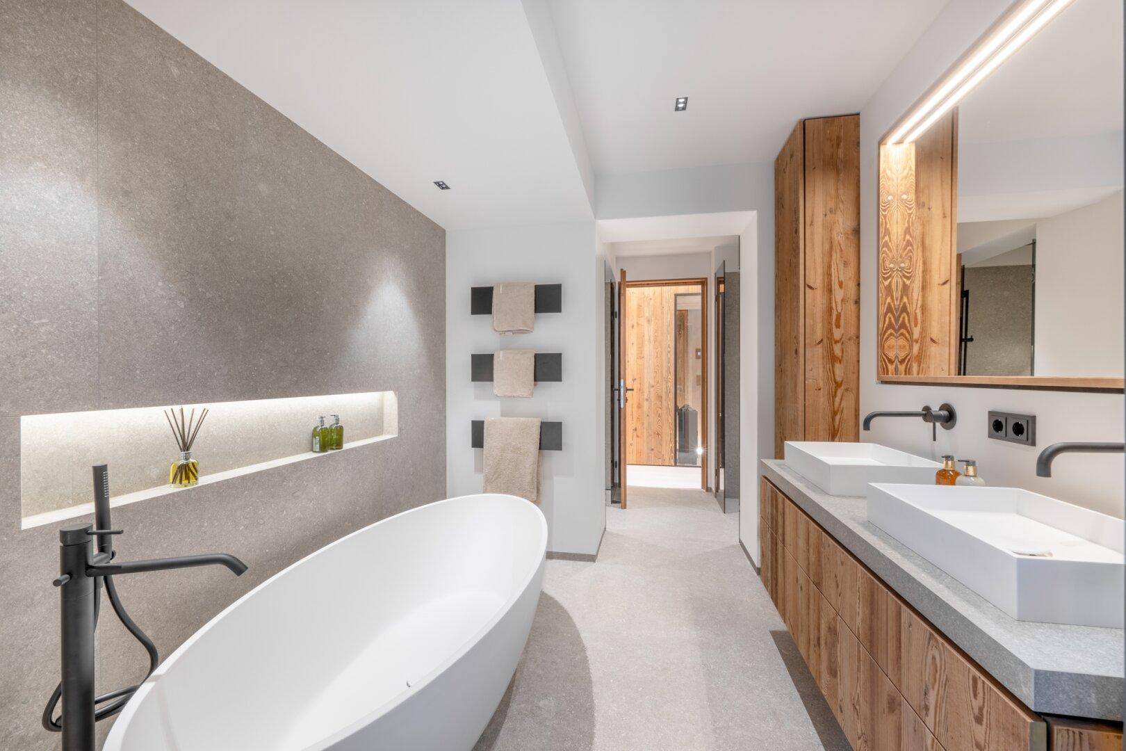 Modernes Badezimmer mit freistehender Badewanne, Doppelwaschbecken und Holzelementen.
