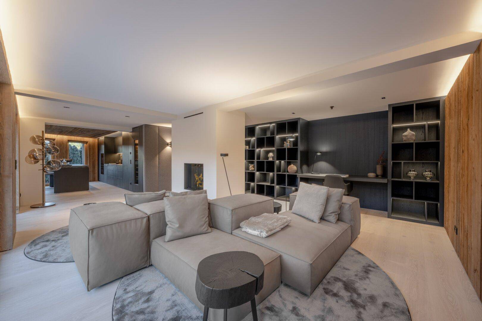 Komfortabler Wohnbereich mit modularem Sofa, integrierten Regalen und Blick auf die offene Küche.