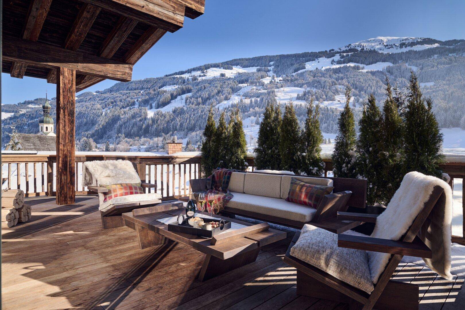 Geräumige Holzterrasse mit gemütlichen Sitzgelegenheiten und atemberaubendem Panoramablick auf die verschneiten Berge.