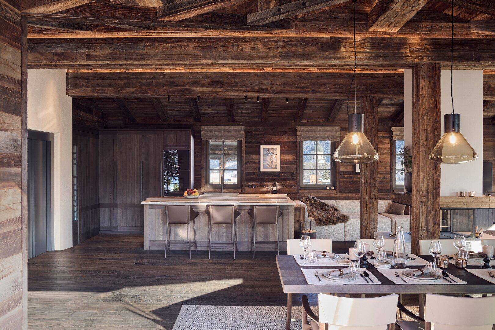 Offene Küche mit Kochinsel und Essbereich, charakterisiert durch rustikale Holzelemente und moderne Ausstattung.