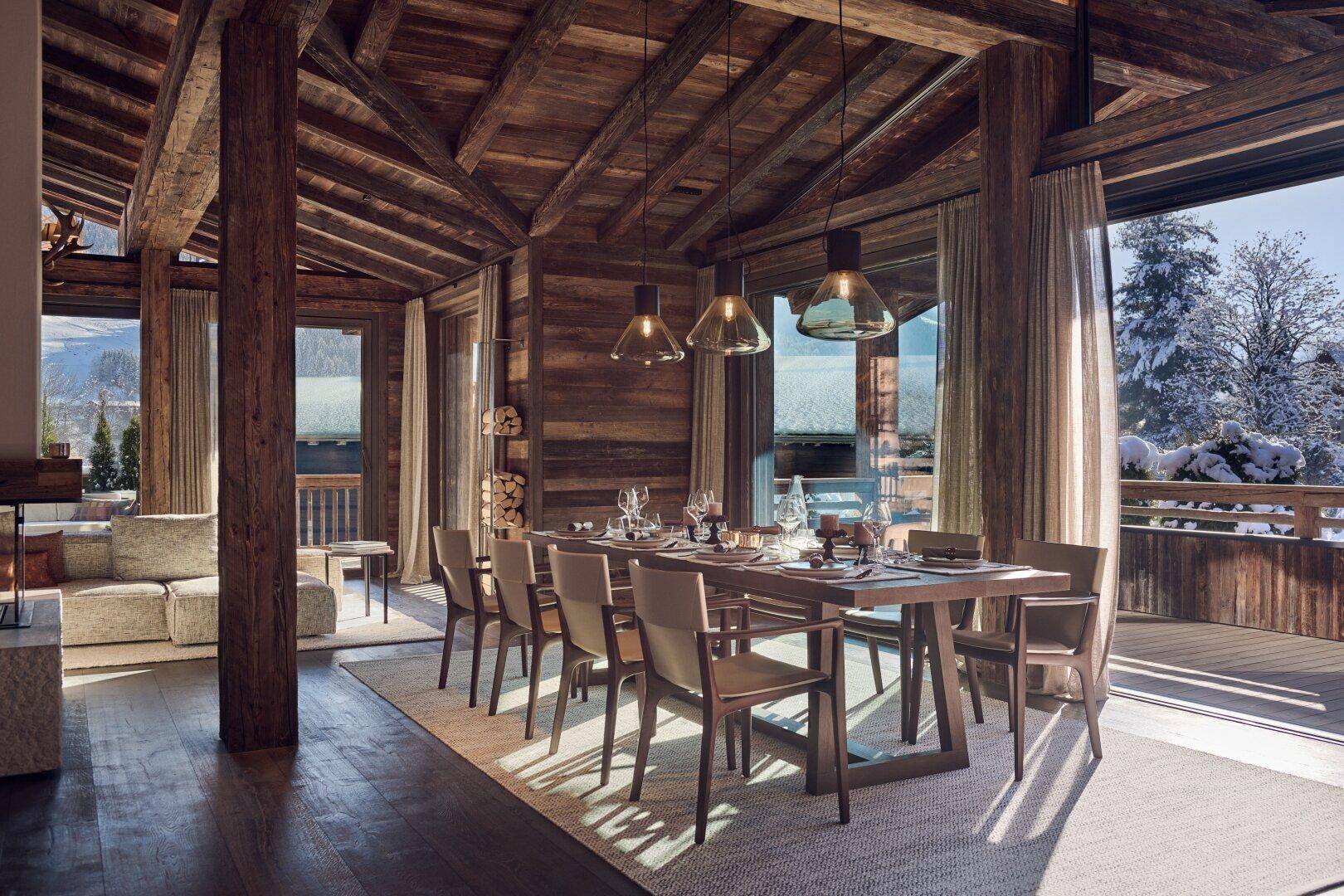 Heller Essbereich mit Holztisch und Stühlen, umgeben von großen Fenstern mit Winterlandschaftsblick.