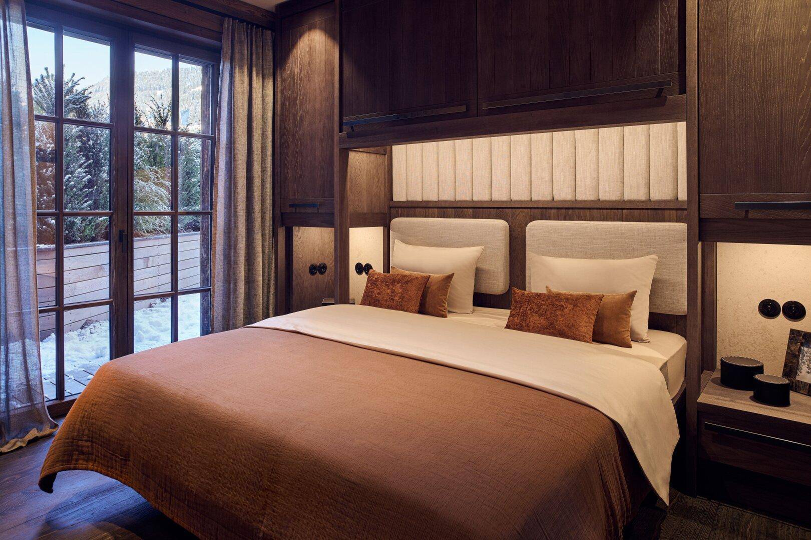 Gemütliches Schlafzimmer mit großem Bett, gepolstertem Kopfteil und Einbauschränken aus dunklem Holz.