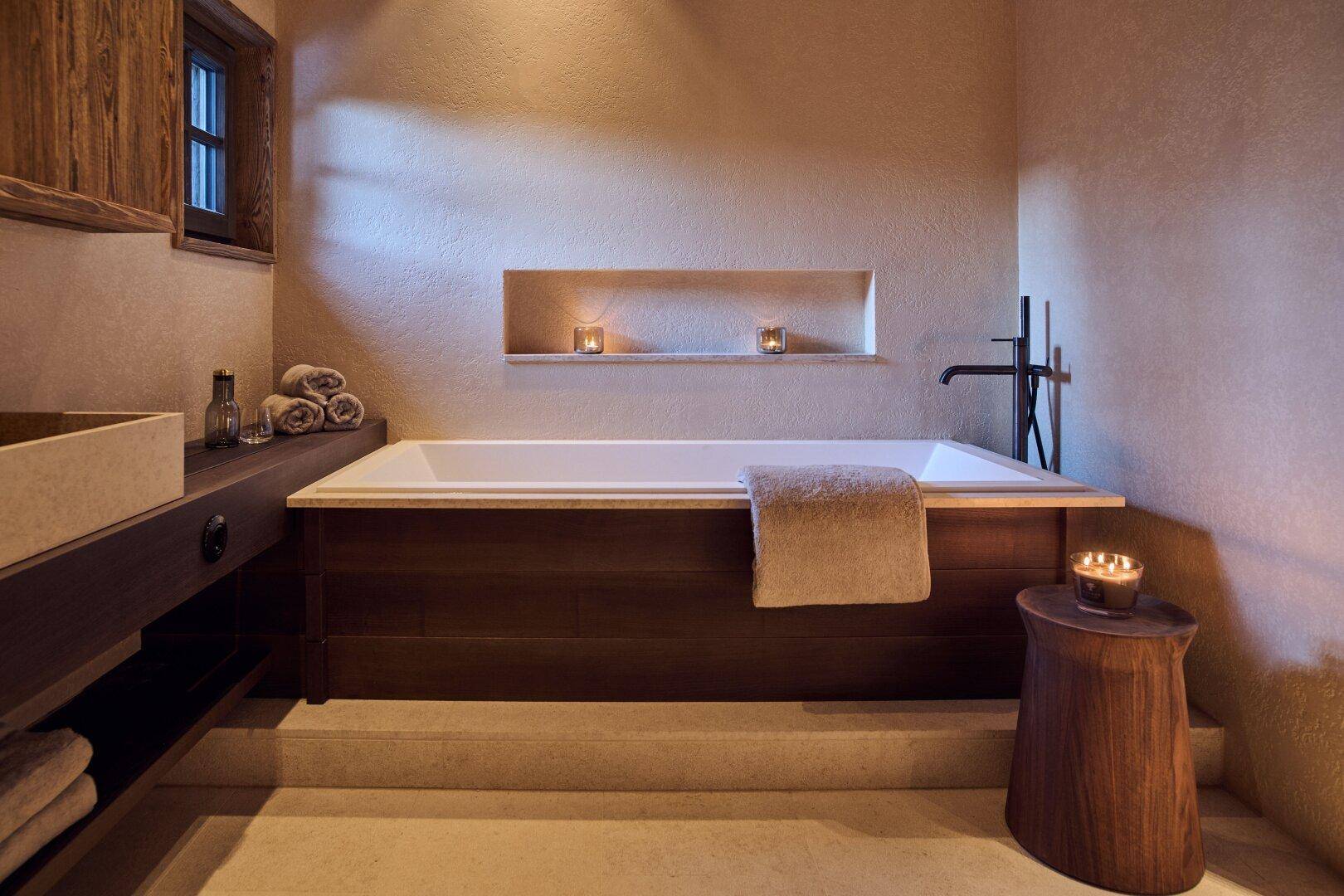 Modernes Badezimmer mit eingebauter Badewanne, Steinsink und indirekter Beleuchtung für entspannte Atmosphäre.