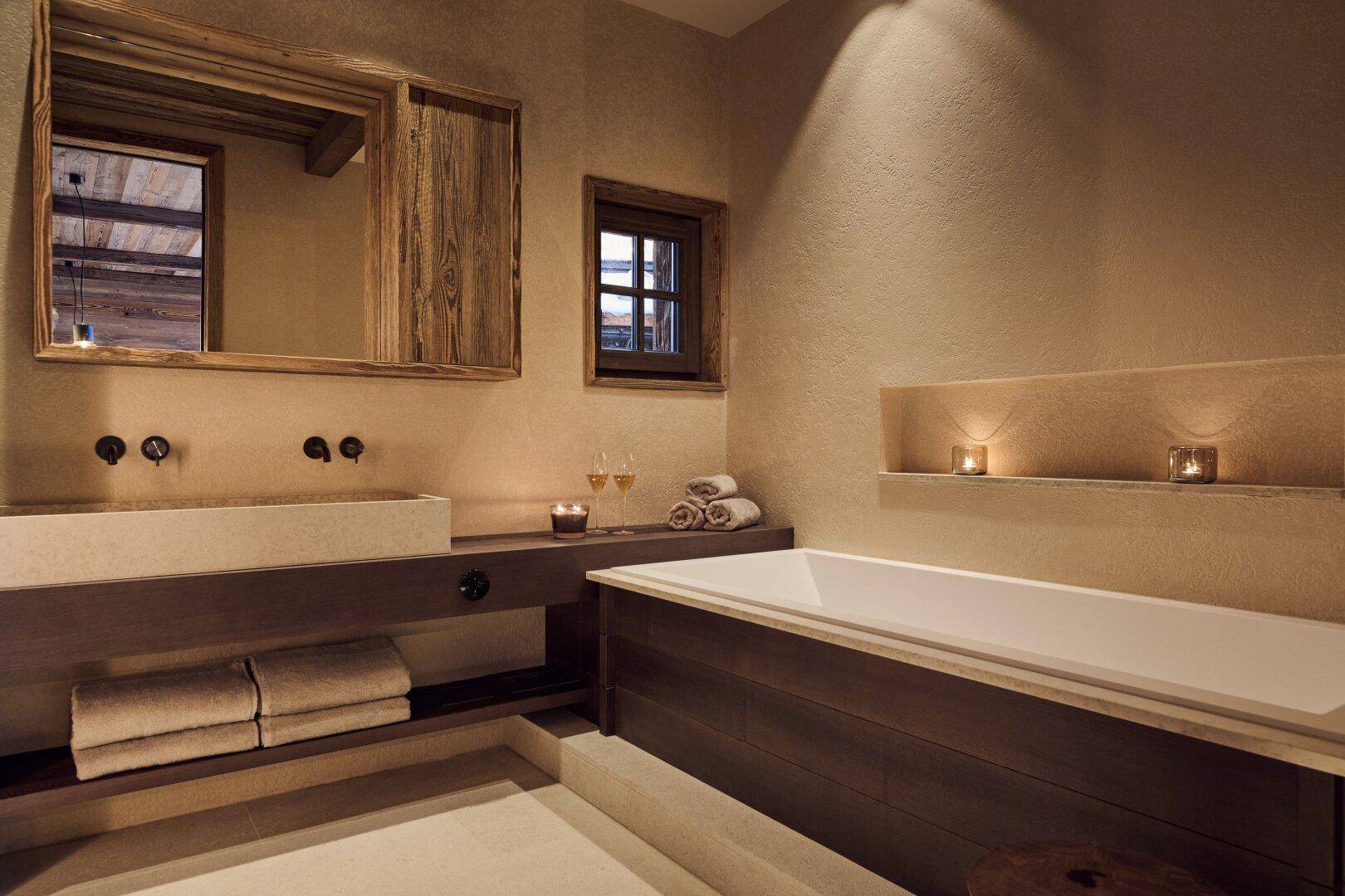 Stilvolles Badezimmer mit Badewanne, Steinsink und einem Holzspiegel, der den rustikalen Charme unterstreicht.