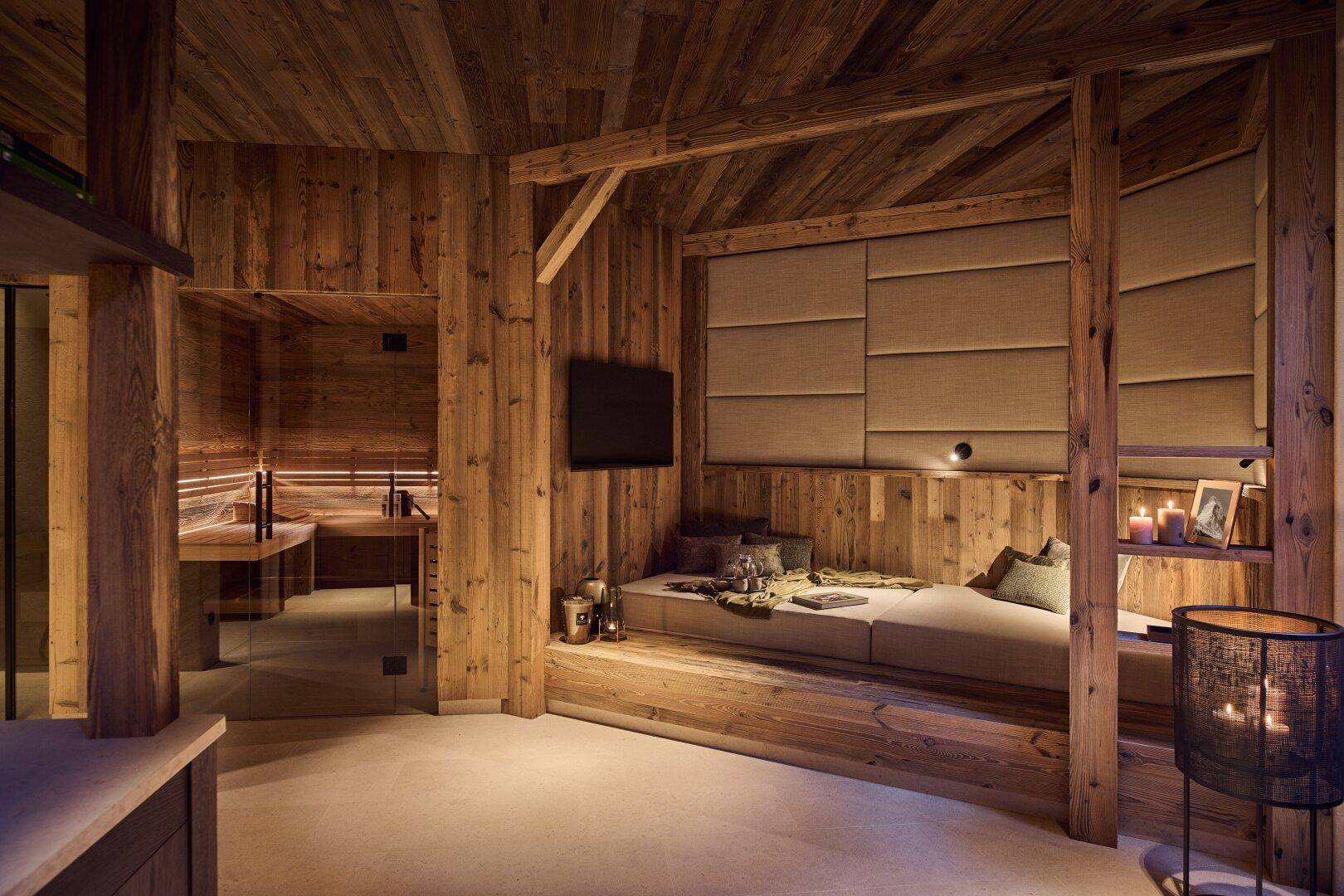 Entspannungsbereich mit Holzvertäfelung, gemütlicher Liegefläche und direktem Zugang zu einer Sauna.