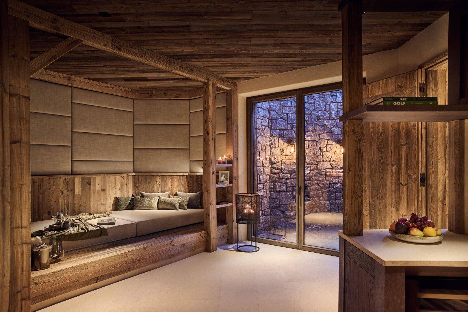 Gemütlicher Wellnessbereich mit Holzvertäfelung und Zugang zu einem privaten Außenbereich mit Steinmauer.
