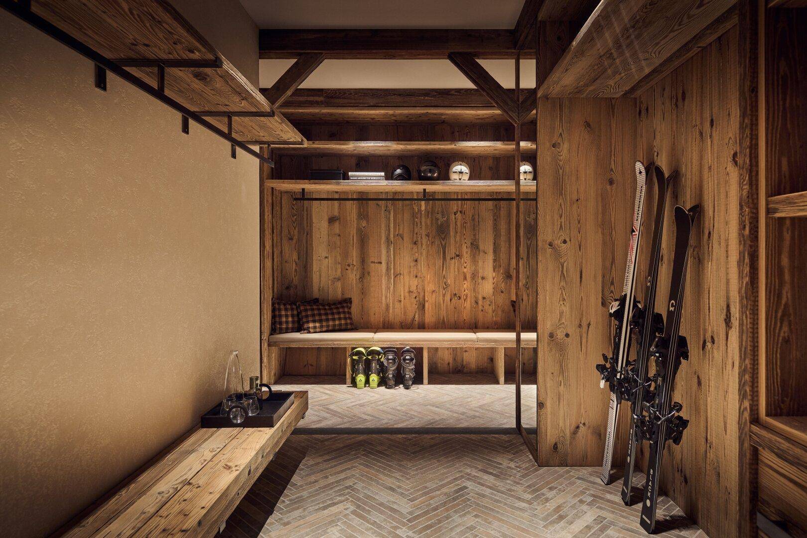 Praktischer Skiraum mit Holzbänken, Stauraum für Skiausrüstung und robustem Fliesenboden.