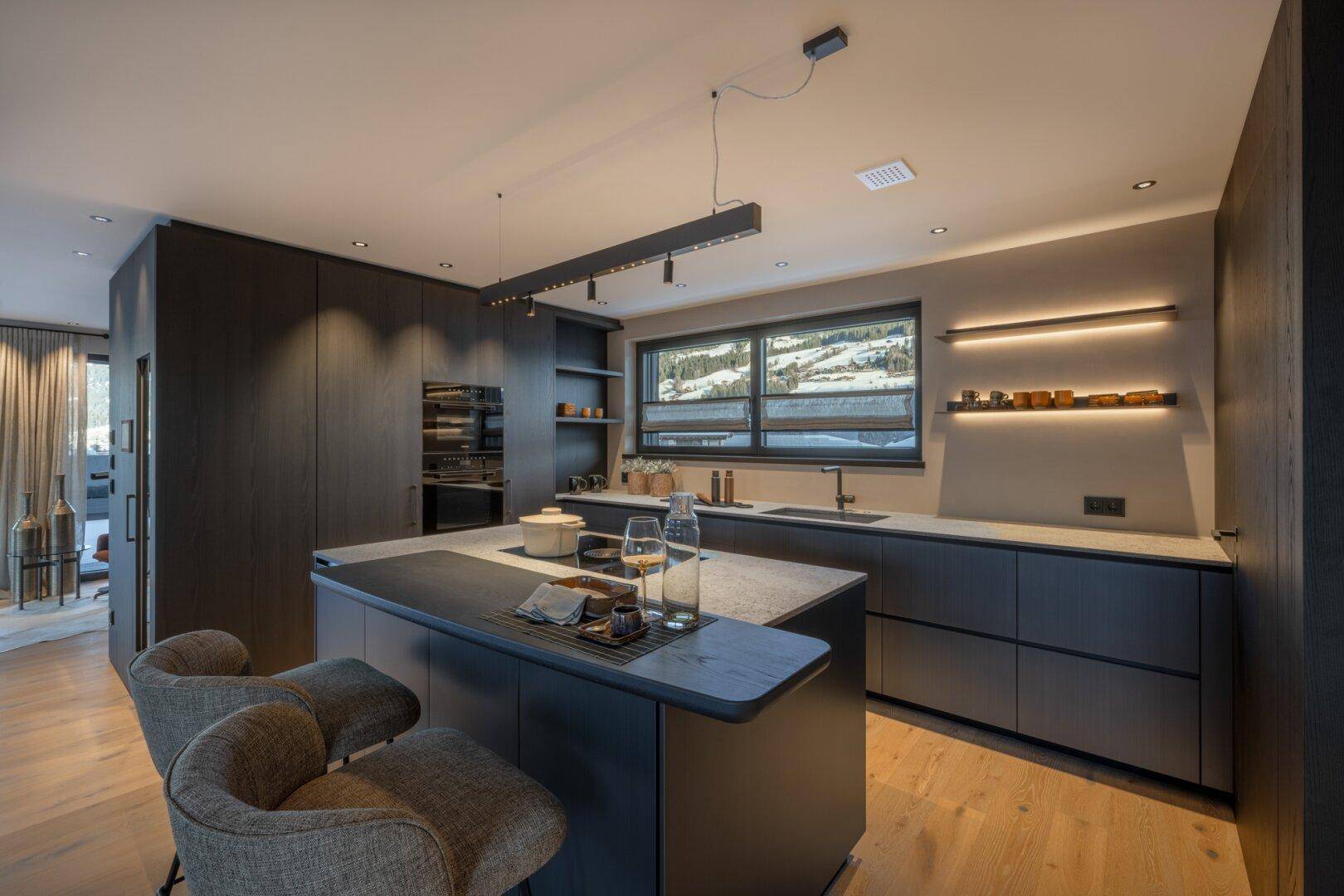 Moderne Küche mit dunklen Holzfronten, Kücheninsel und integrierten Geräten für ein luxuriöses Kocherlebnis.