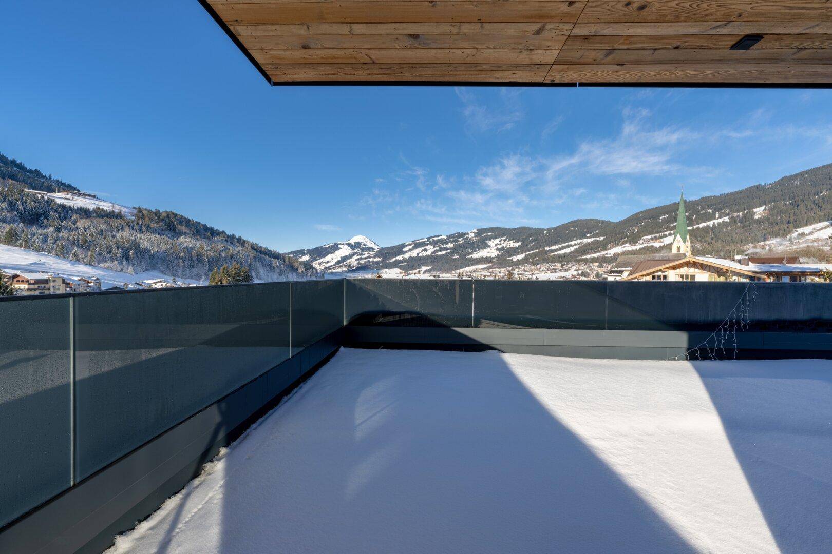 Große, schneebedeckte Terrasse mit Panoramablick auf die umliegende Berglandschaft.