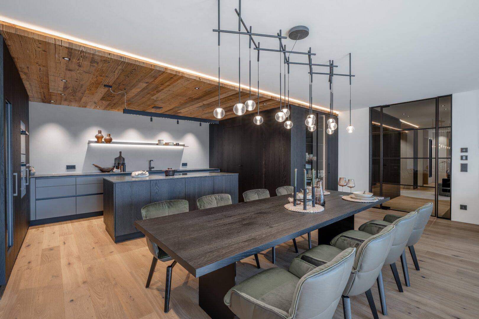 Moderner Essbereich mit Holztisch, stilvollen Stühlen und offener Küche mit Holzdecke.