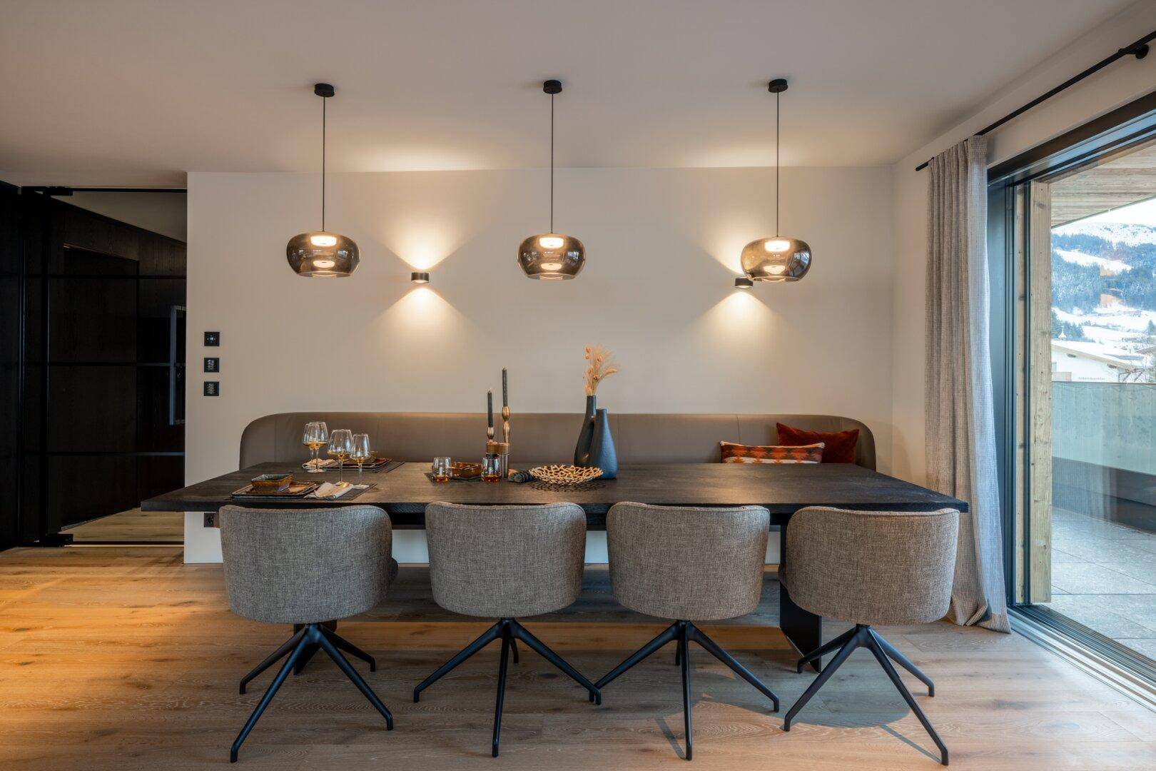 Stilvoller Essbereich mit langer Sitzbank, Holztisch und Pendelleuchten, ideal für gesellige Runden.