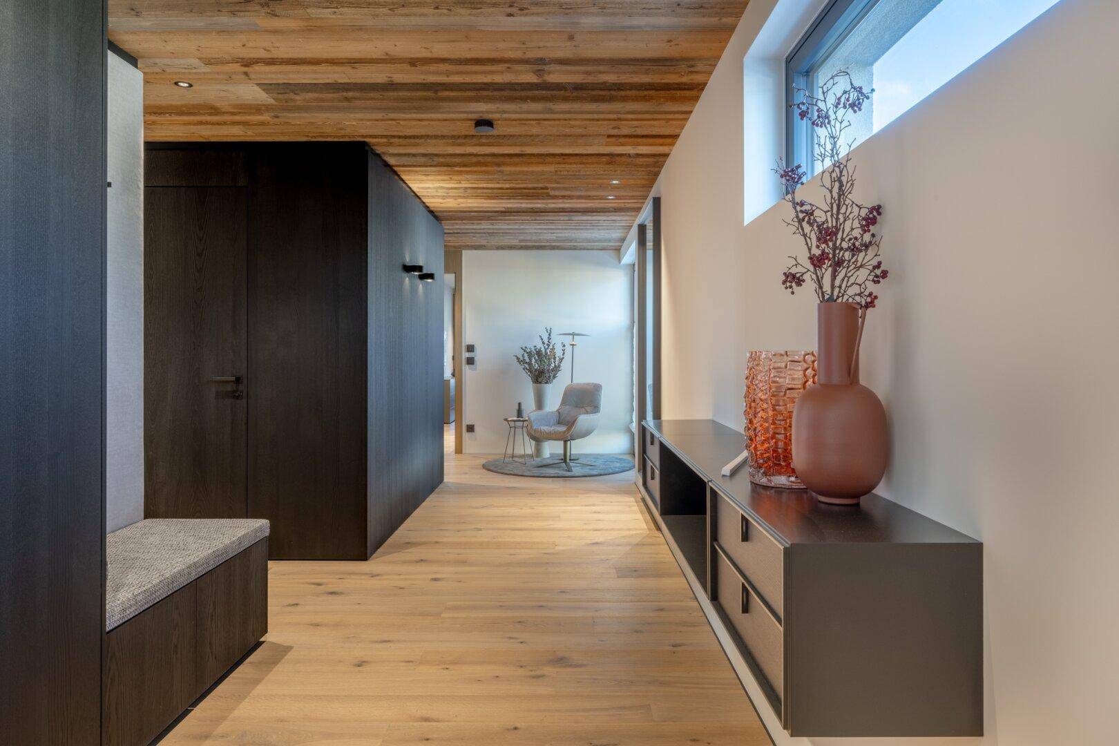 Heller Flur mit Holzboden, Holzdecke und moderner Konsole mit Dekoration.