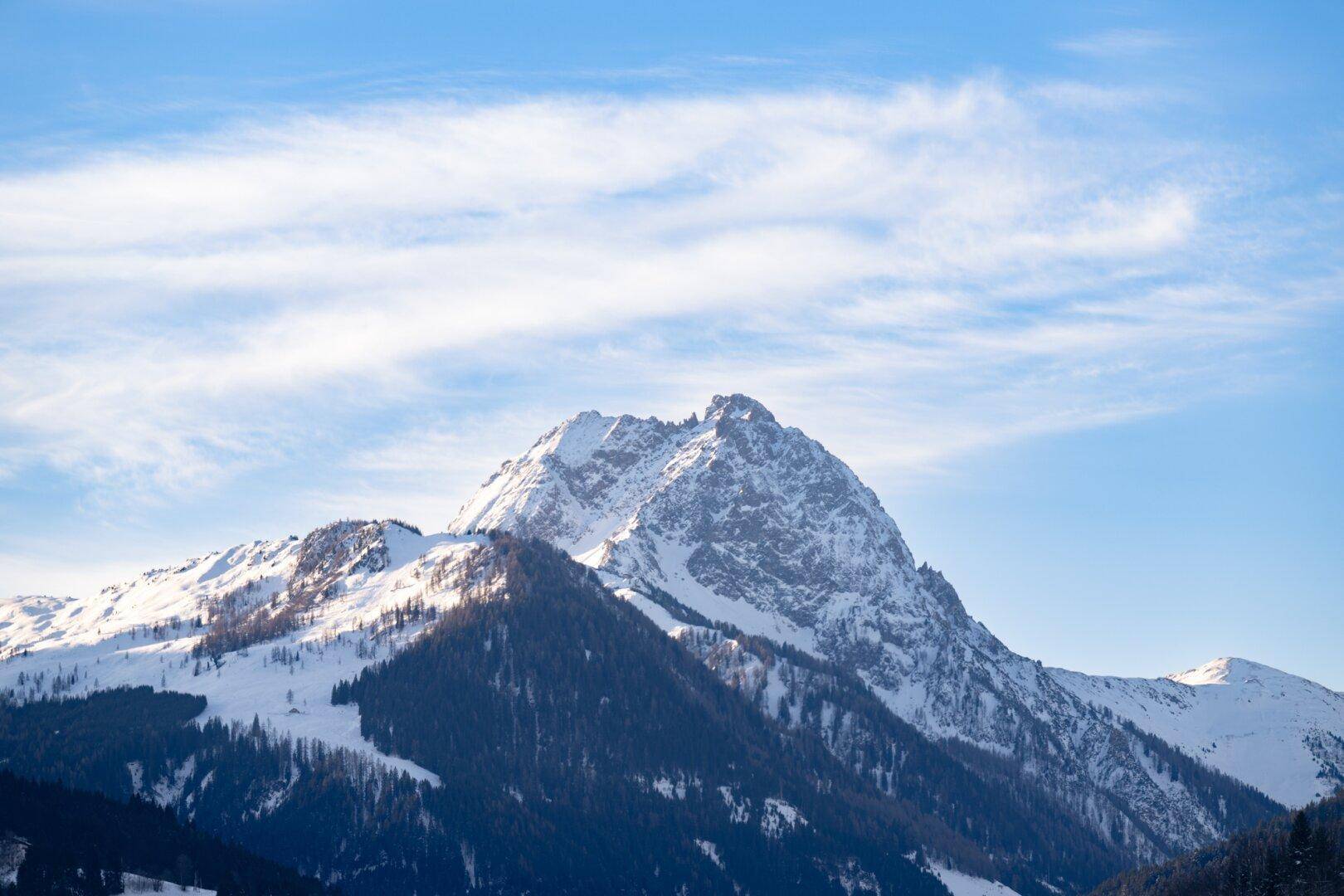 Spektakulärer schneebedeckter Berggipfel unter einem teilweise bewölkten Himmel.