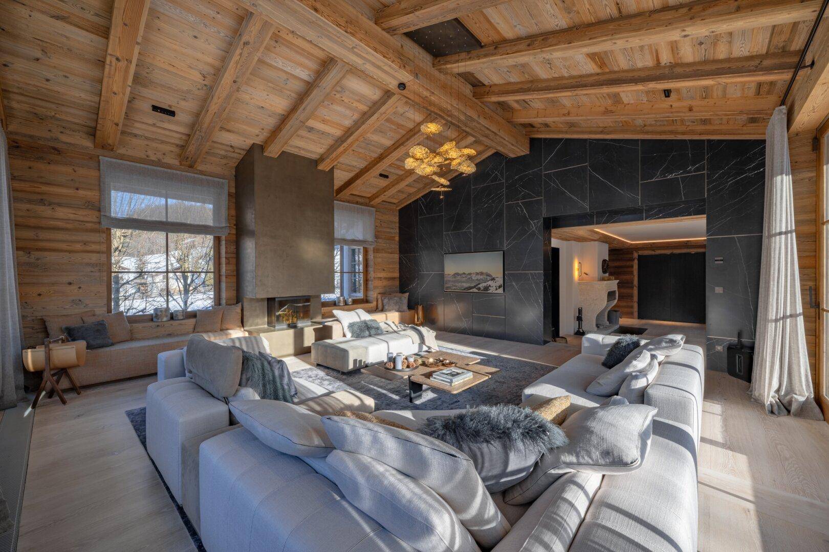Luxuriöses Wohnzimmer mit Holzbalkendecke, modernem Kamin und stilvoller Einrichtung.
