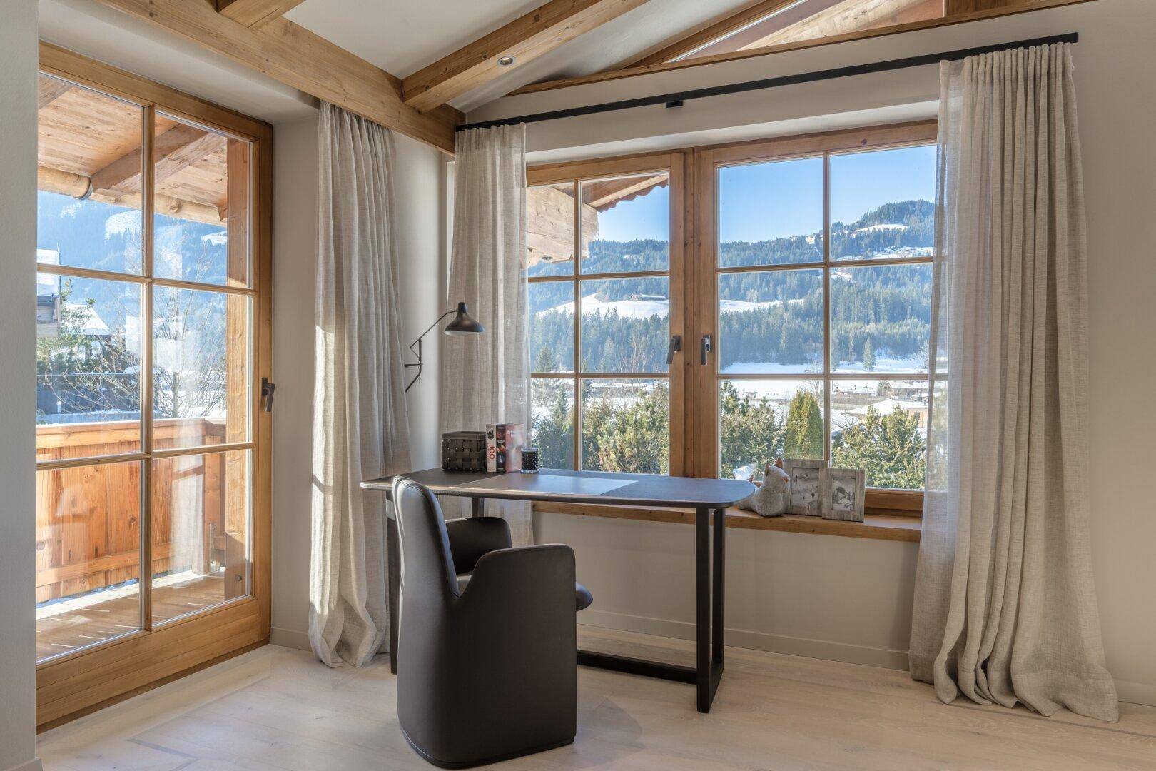 Helles Arbeitszimmer mit Holzboden, großen Fenstern und inspirierendem Blick auf die Berglandschaft.