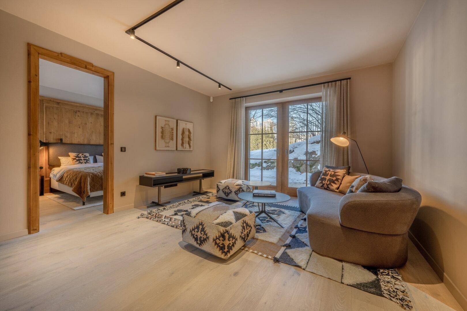 Gemütlicher Wohnbereich mit Sitzgelegenheiten, Teppich und Zugang zu einem Schlafzimmer.
