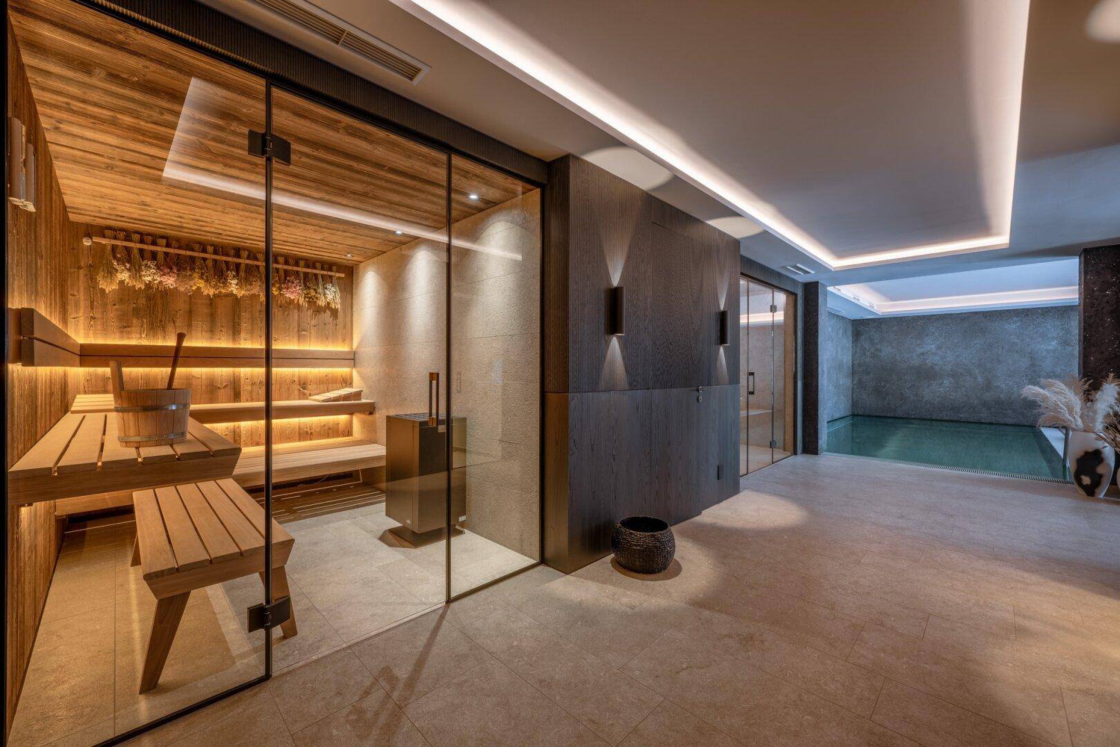 Luxuriöser Wellnessbereich mit Sauna, Innenpool und stilvoller Beleuchtung.