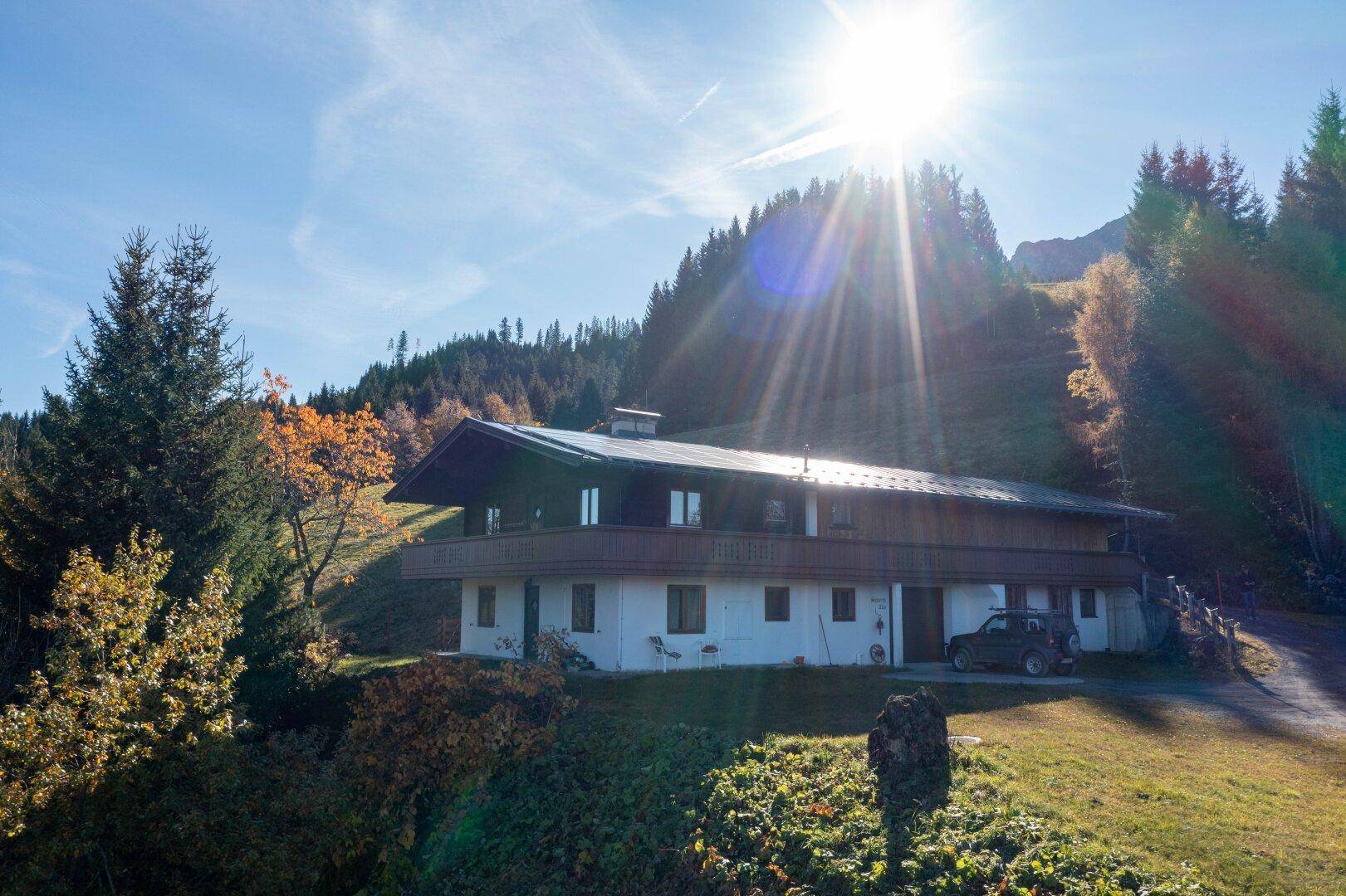 Charmantes Haus in sonniger Hanglage mit Holzbalkon und umgebenden Wäldern.
