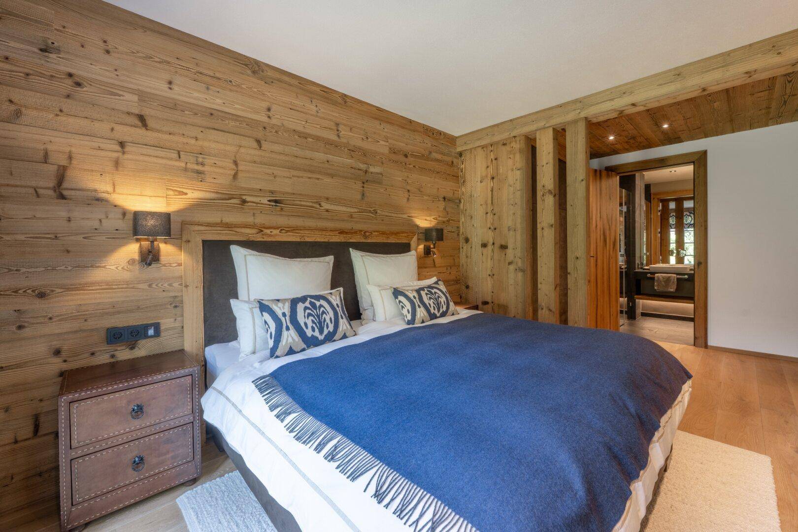 Komfortables Schlafzimmer mit Holzwänden und Holzbalken, ausgestattet mit einem großen Doppelbett.